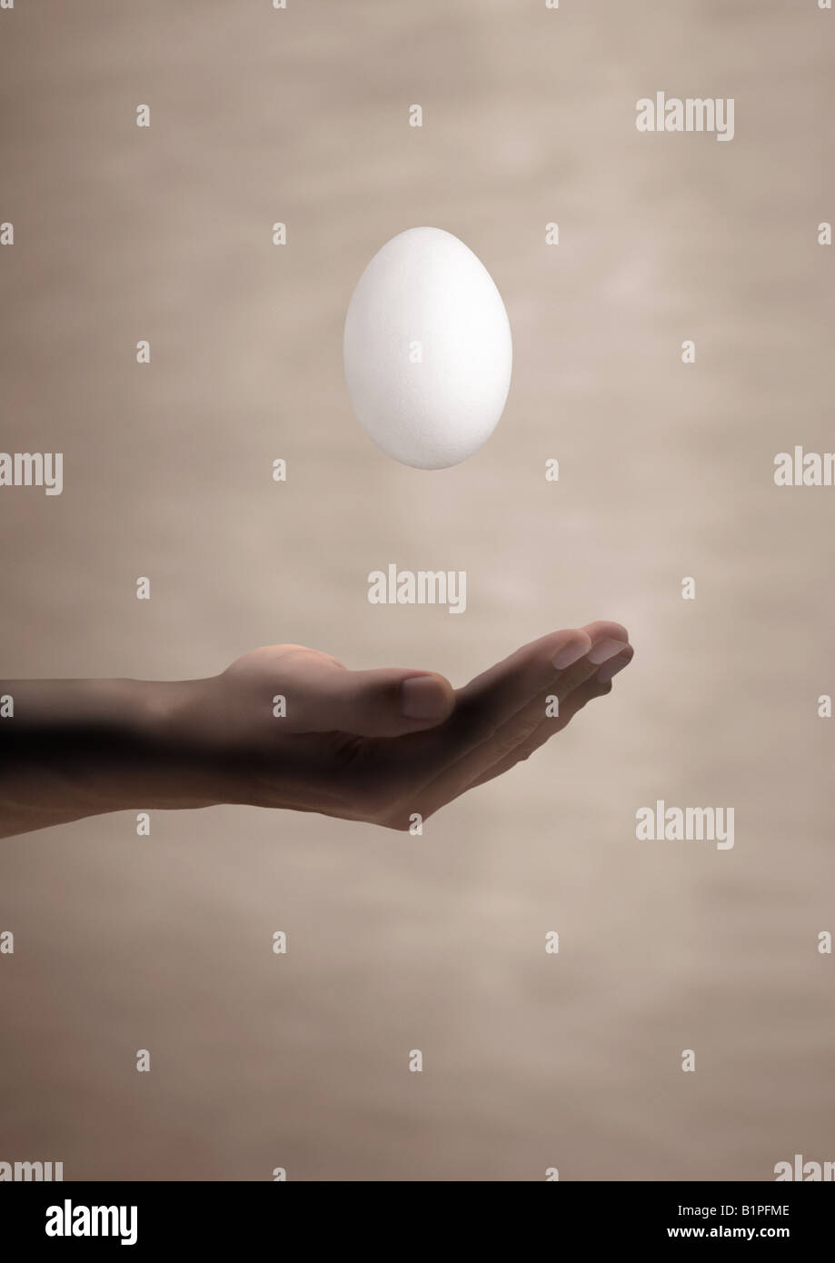 Uovo flottante schwebendes fallendes Ei über einer mano Foto Stock