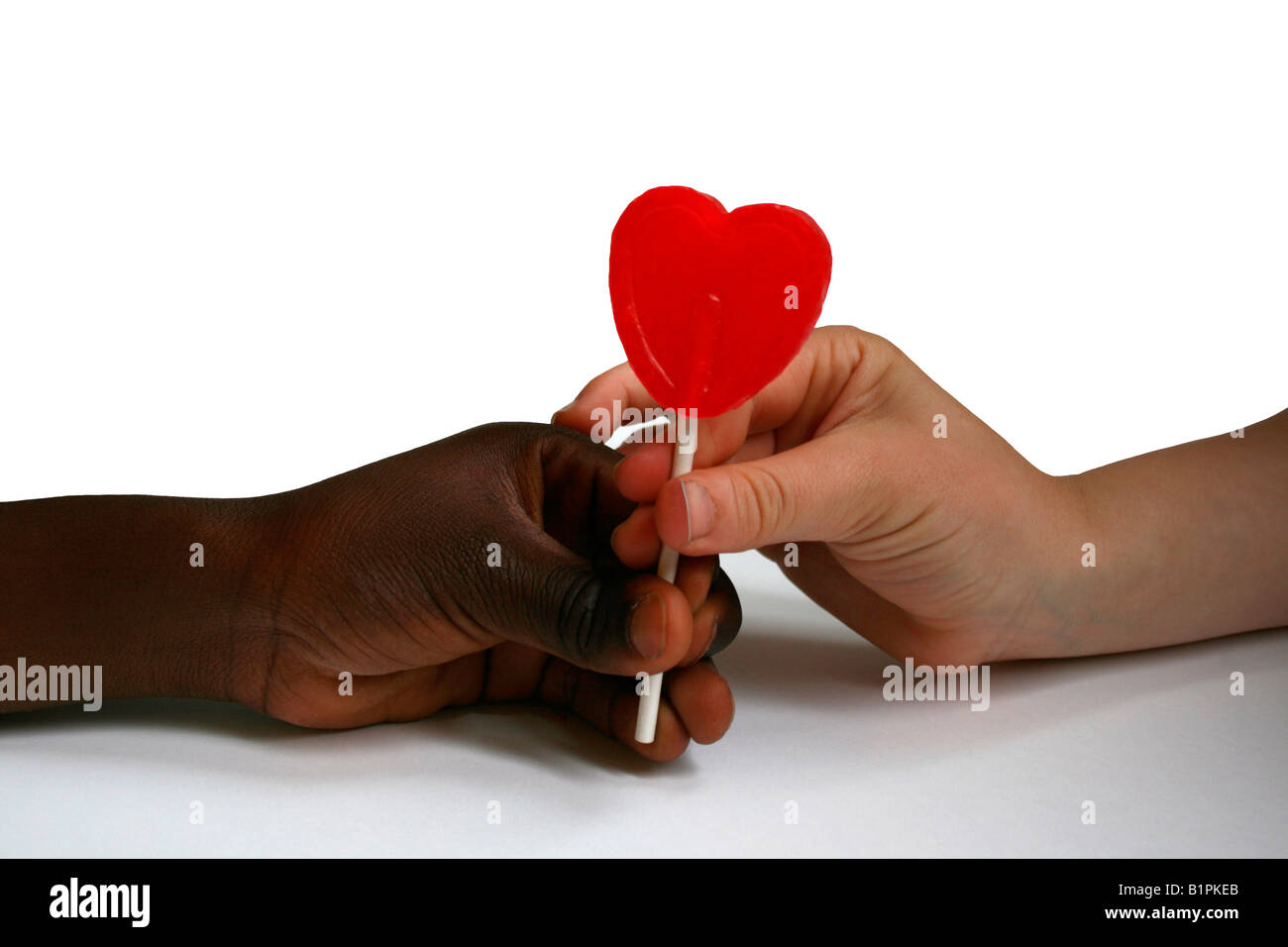 I bambini con le mani in mano tenendo un a forma di cuore ad lecca-lecca Foto Stock