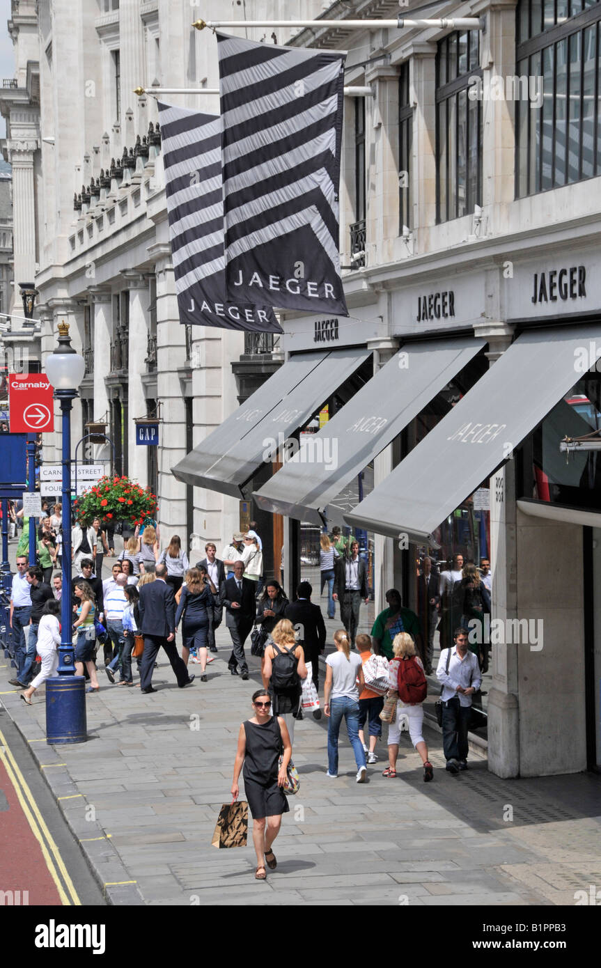 Gli amanti dello shopping a piedi la pavimentazione di Regent Street al di fuori delle vetrine del negozio Jaeger Foto Stock