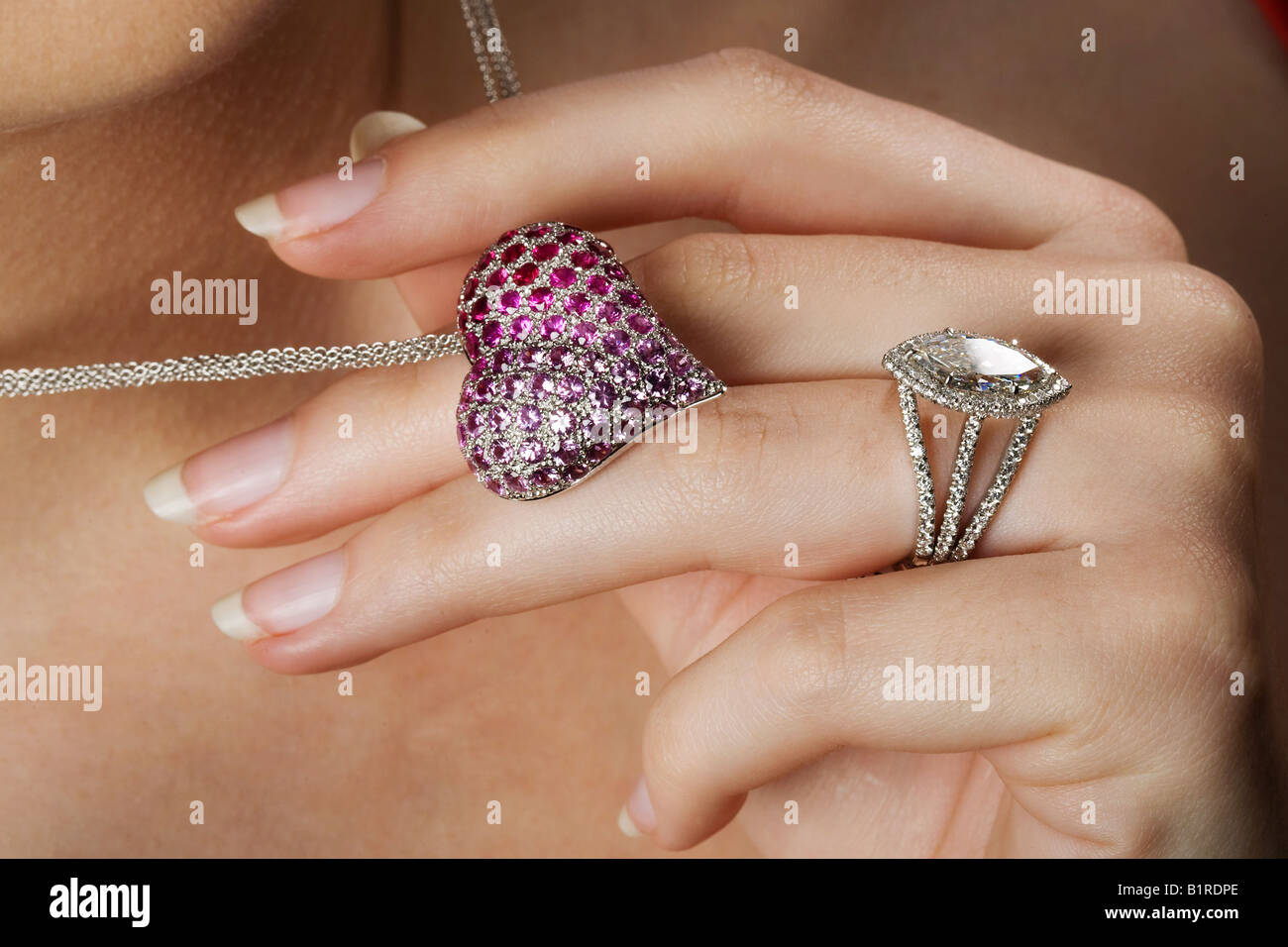 Una donna che sorregge una gemma chiodati a forma di cuore collana indossando un brillante anello diamante. Foto Stock