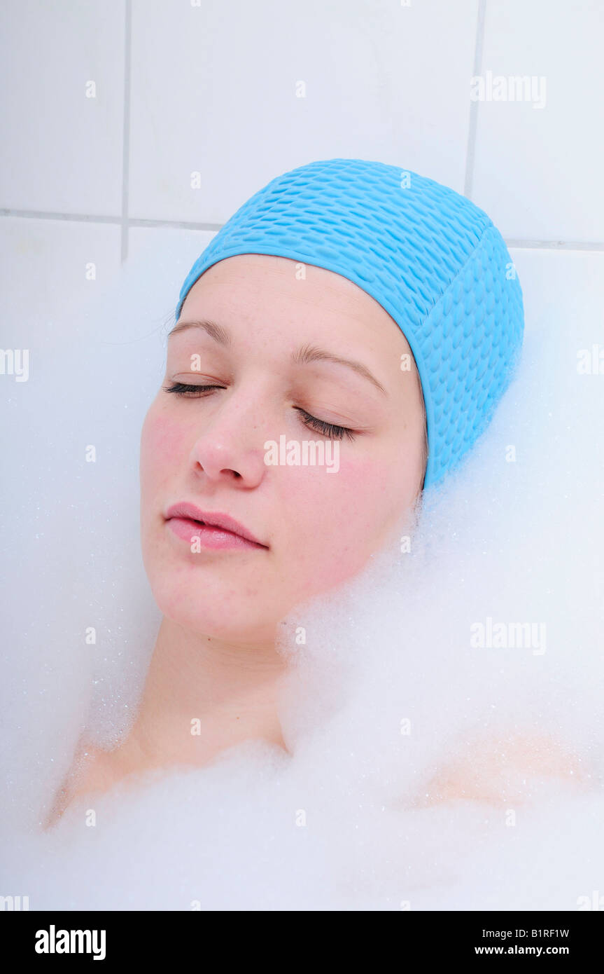 Piuttosto giovane donna tenendo bagno nella vasca da bagno e rilassante, blu della cuffia Foto Stock