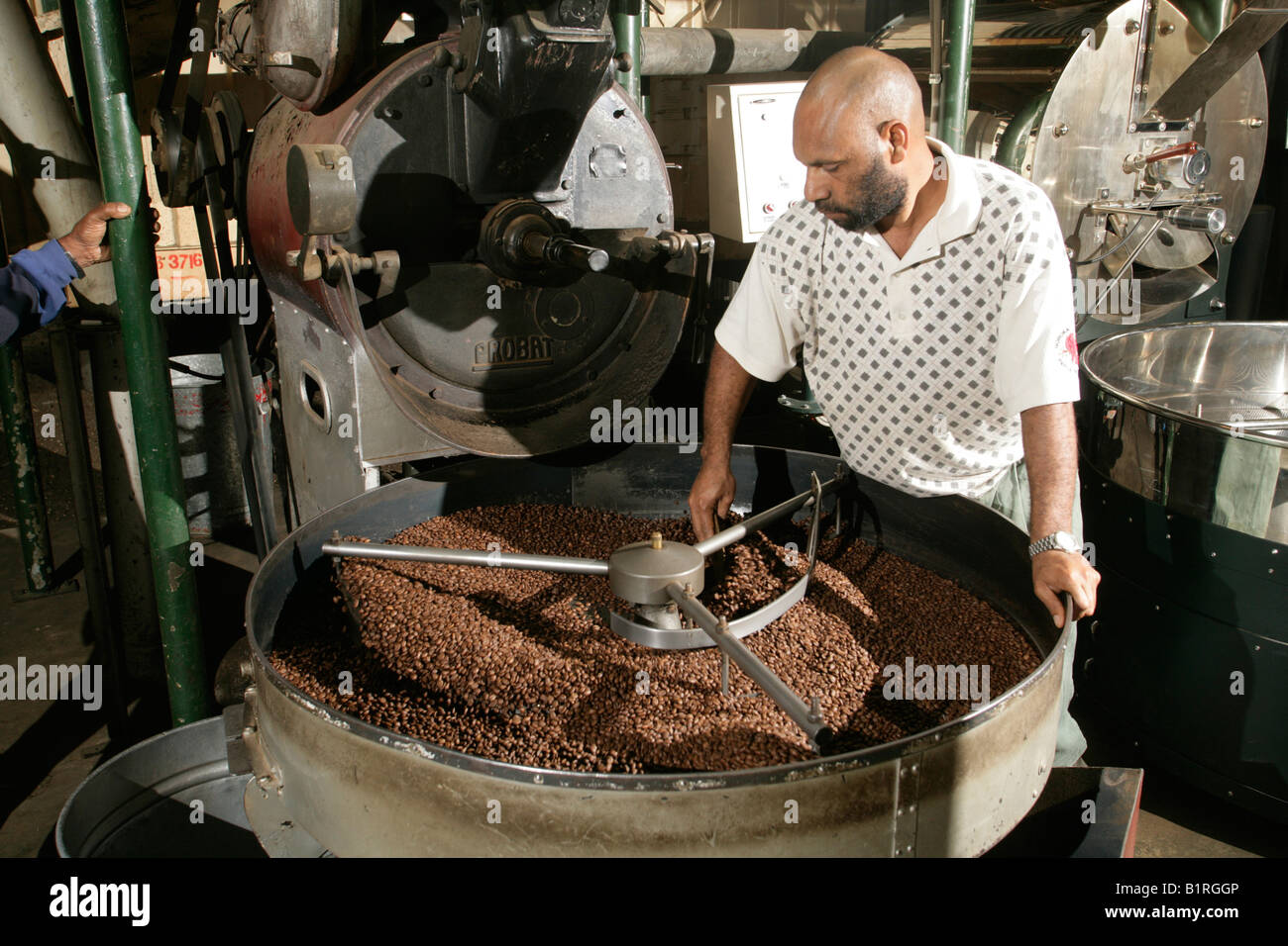 Un uomo in un roastery è torrefazione di caffè, Goroka, Papua Nuova Guinea, Melanesia Foto Stock