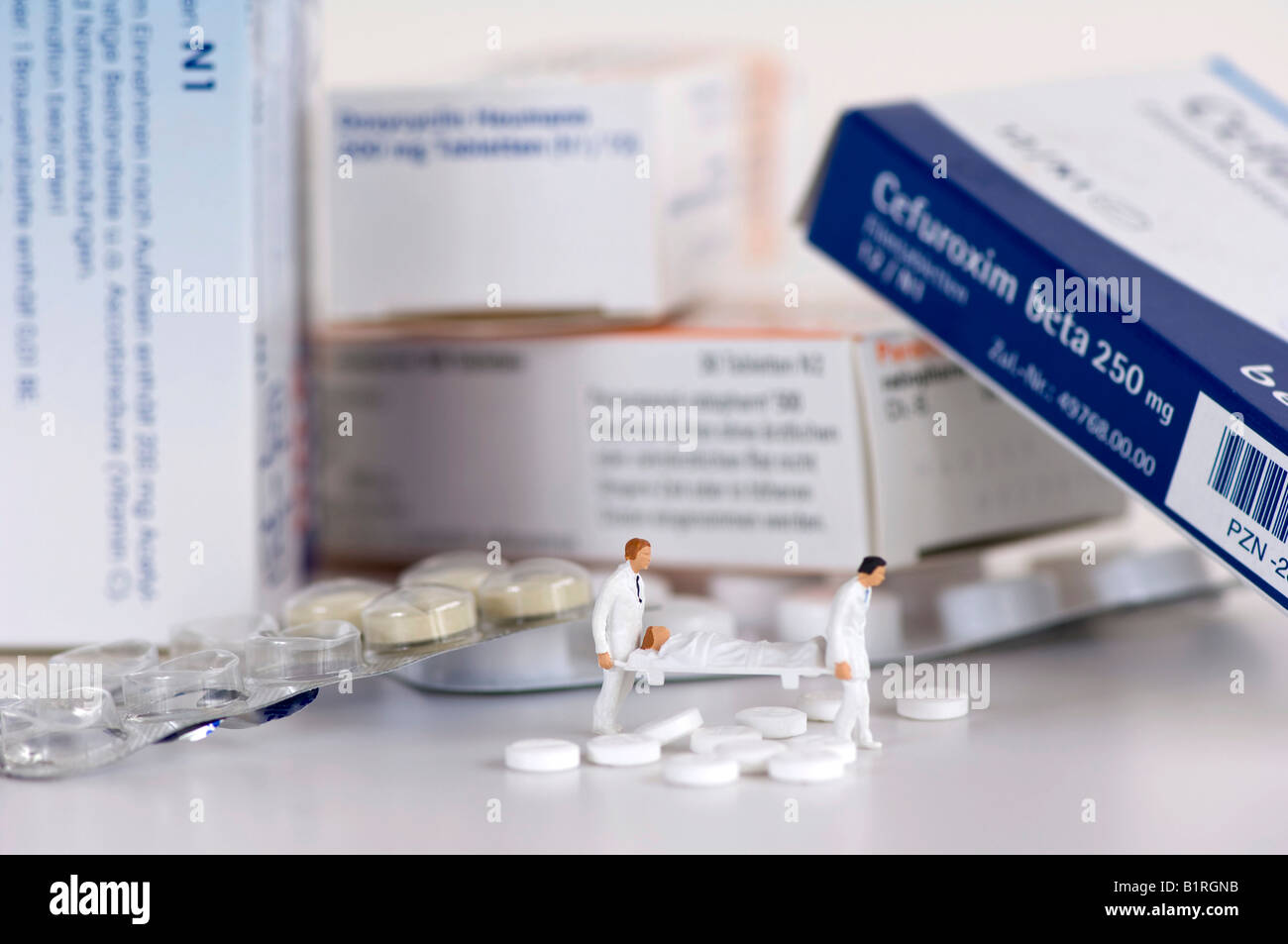 Compresse, blister, tablet scatole e paramedici in miniatura che porta una donna su una barella, simbolico foto Foto Stock