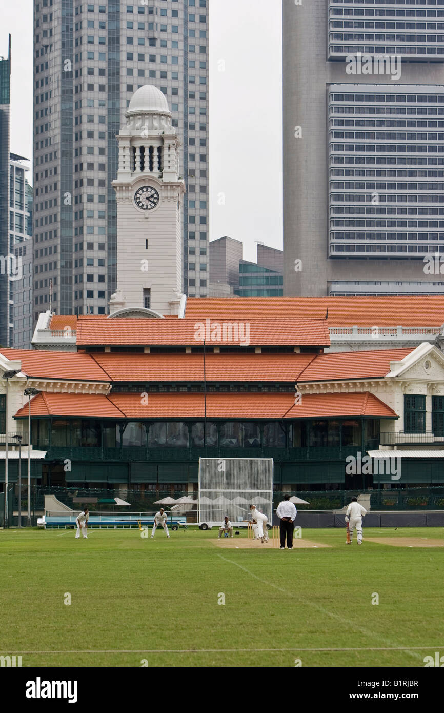 I giocatori di cricket a giocare sul campo di cricket del Singapore Cricket Club, istituito nel 1852, grattacieli di Singapore F Foto Stock