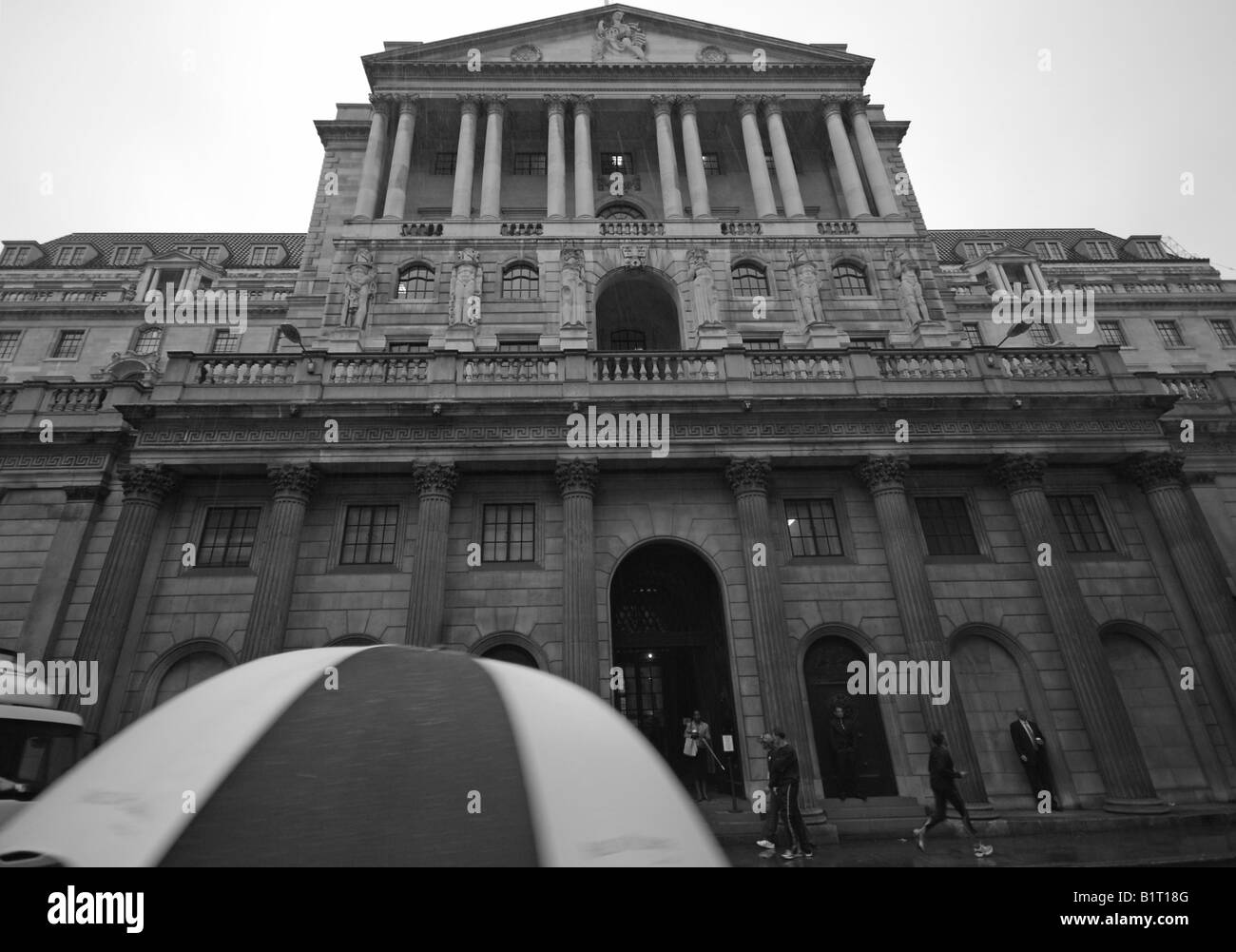 Bank of England, con ombrellone in primo piano sotto cieli di pioggia, in bianco e nero (versione a colori disponibili) Foto Stock