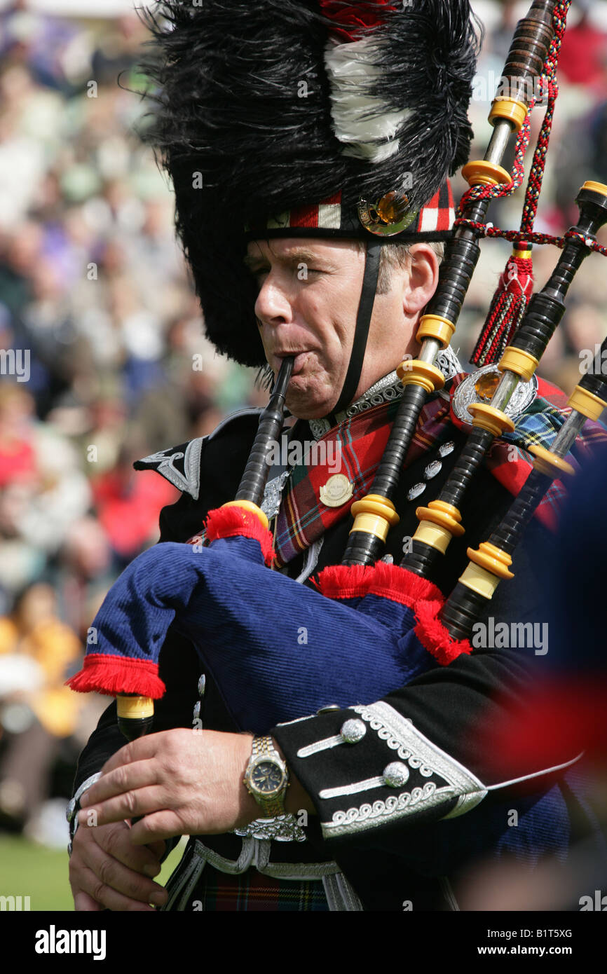 Villaggio di Braemar, Scozia. Scottish piper competere nel pipe band della concorrenza a Braemar giochi in una giornata di vento. Foto Stock