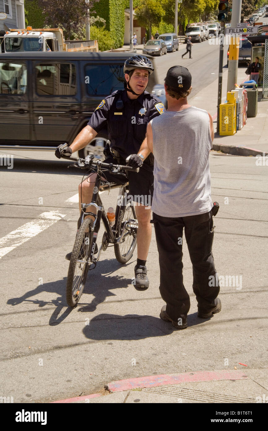 Una bicicletta montata poliziotto chat con un passerby su Fillmore Street di San Francisco s Pacific Heights neighborhood Foto Stock