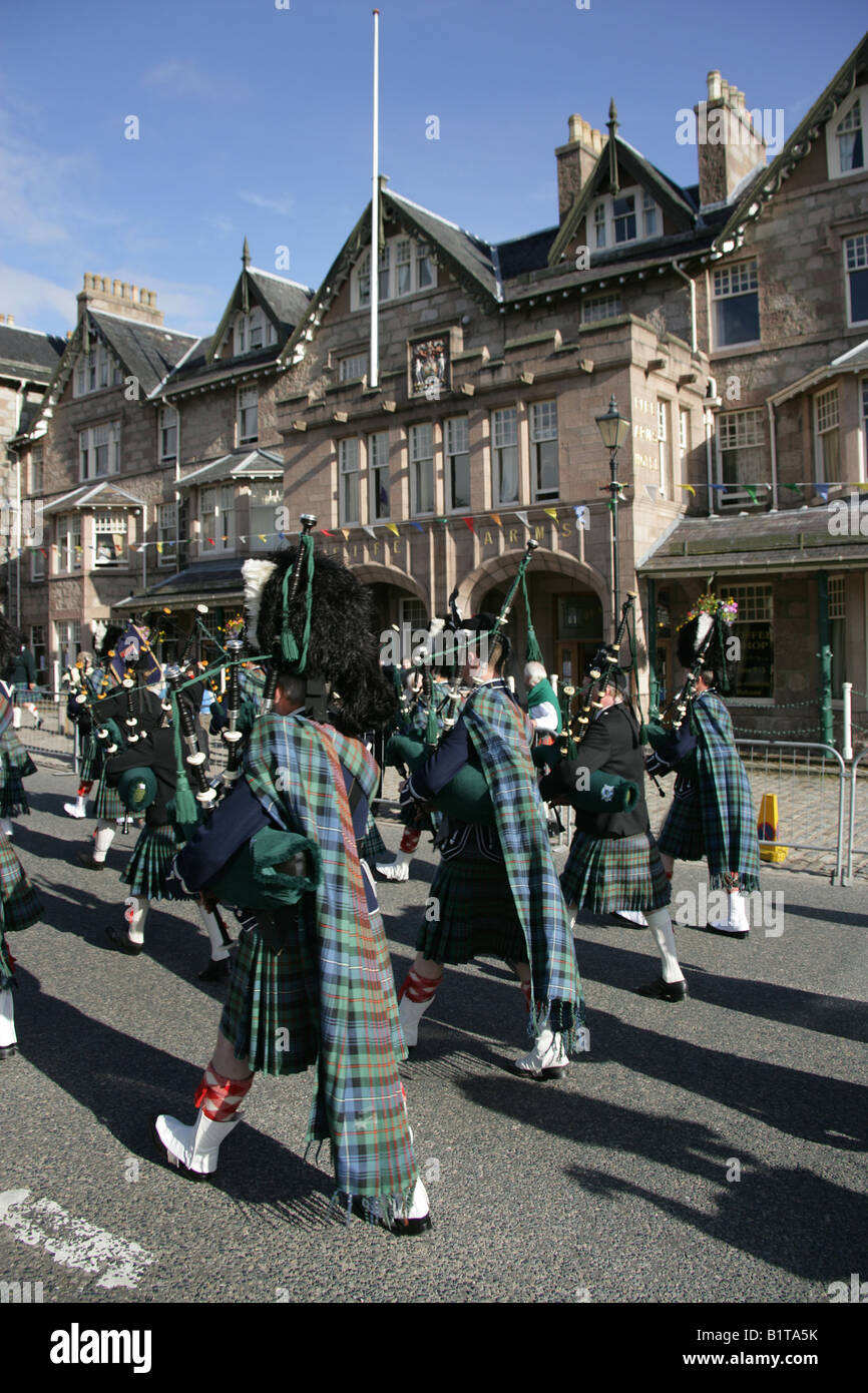 Villaggio di Braemar, Scozia. Pipe Band marciando attraverso Braemar village, con la Fife Arms Hotel in background. Foto Stock