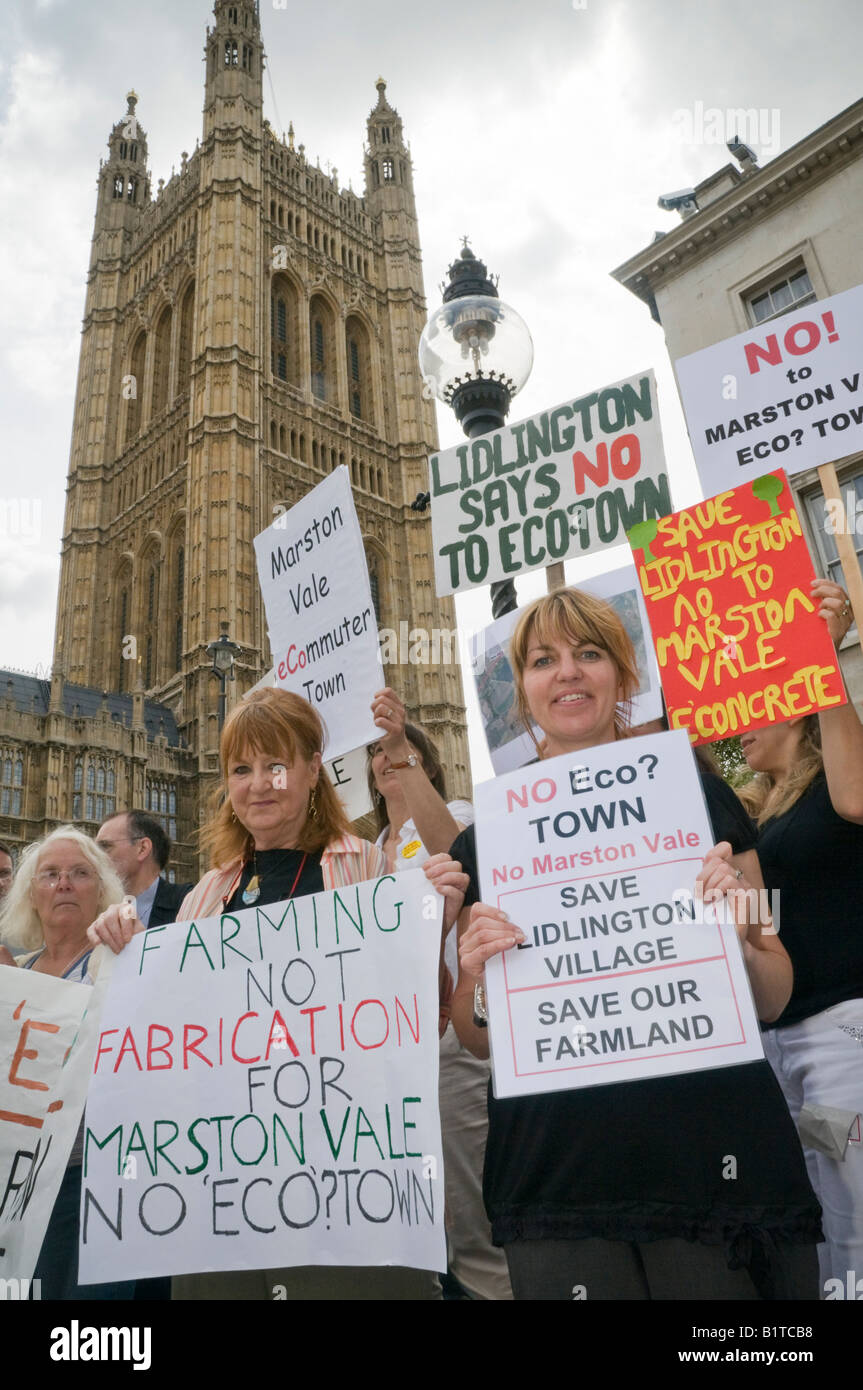 Manifestanti contro un eco-città a Marston Vale, letti con cartelloni fuori le case del Parlamento alla eco-town hall Foto Stock