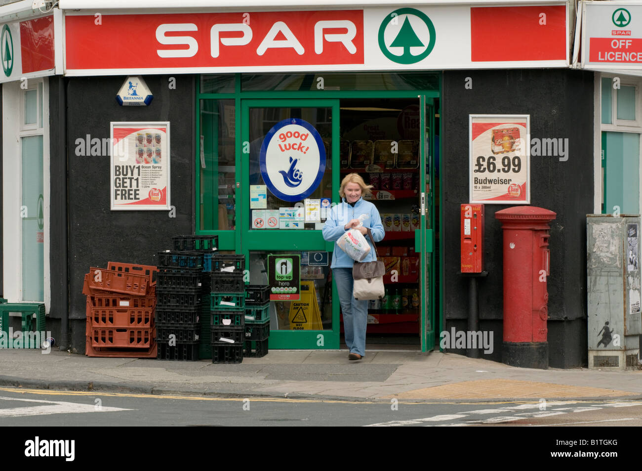 Spar piccolo angolo locale shop convenience food store franchising - donna shopper a piedi al di fuori del negozio con lo shopping, REGNO UNITO Foto Stock