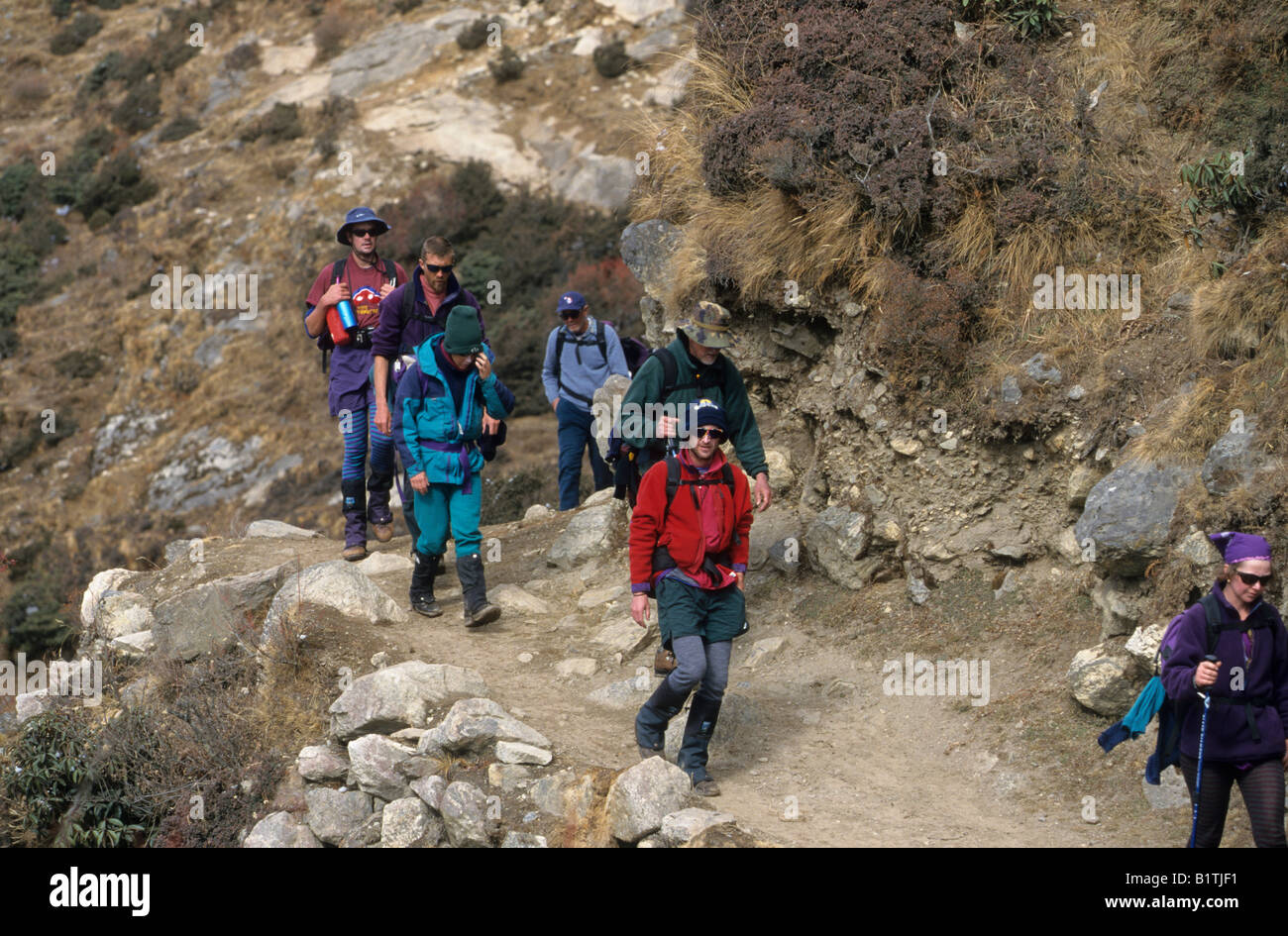 I turisti occidentali escursione lungo una montagna himalayana trail nel Thamo, Nepal Foto Stock