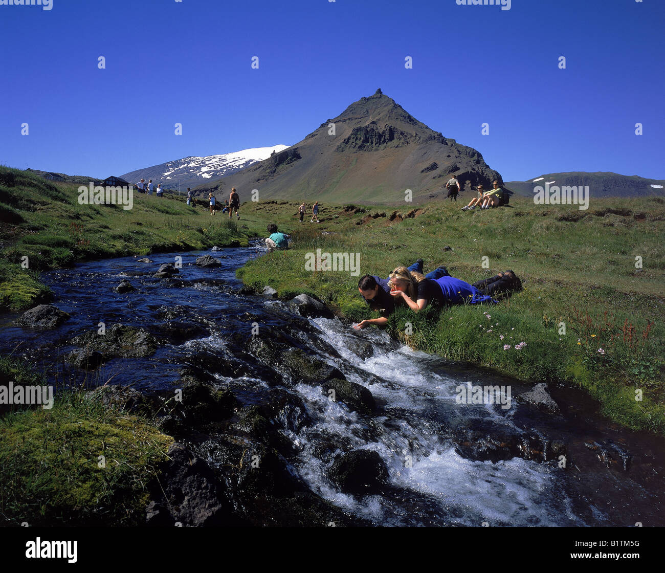 Gli escursionisti di bere dal flusso in Islanda Foto Stock