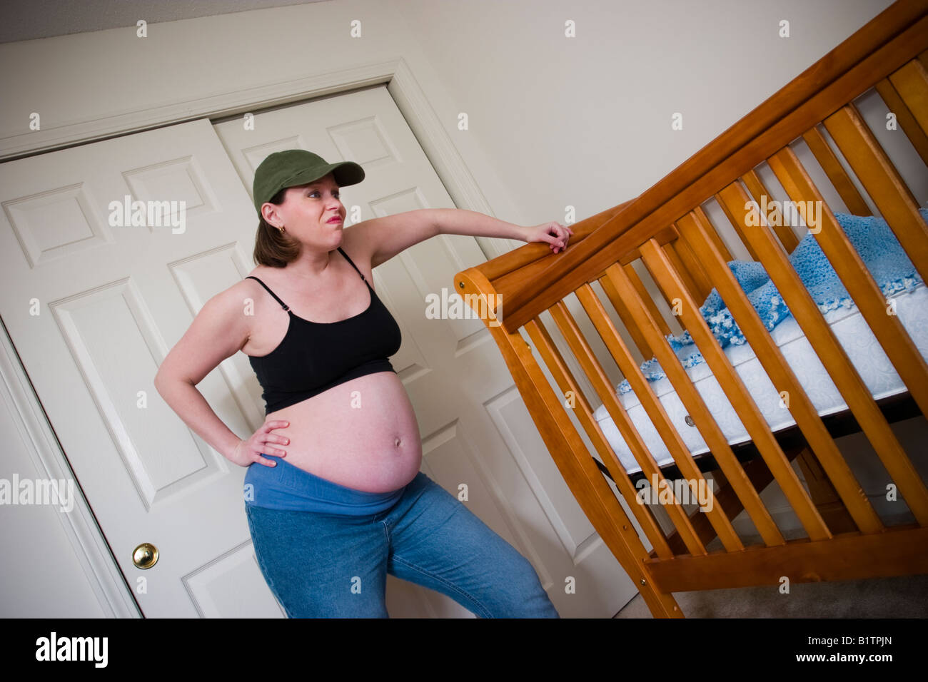 Donna incinta appoggiata sul presepe nella baby camera s modello rilasciato Foto Stock
