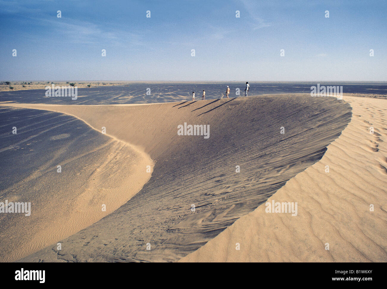 Famiglia caucasica e guida africana a piedi sulla cresta della mezzaluna scolpite di Barchan o trasversale duna di sabbia Kenya Africa orientale Foto Stock