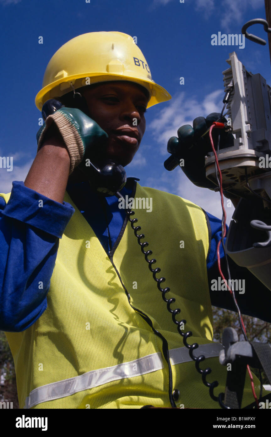 Il Botswana Sud Africa lavorano persone ritratto maschile di tirocinante ingegnere elettrico lavorando su cassetta terminale tramite il telefono Foto Stock