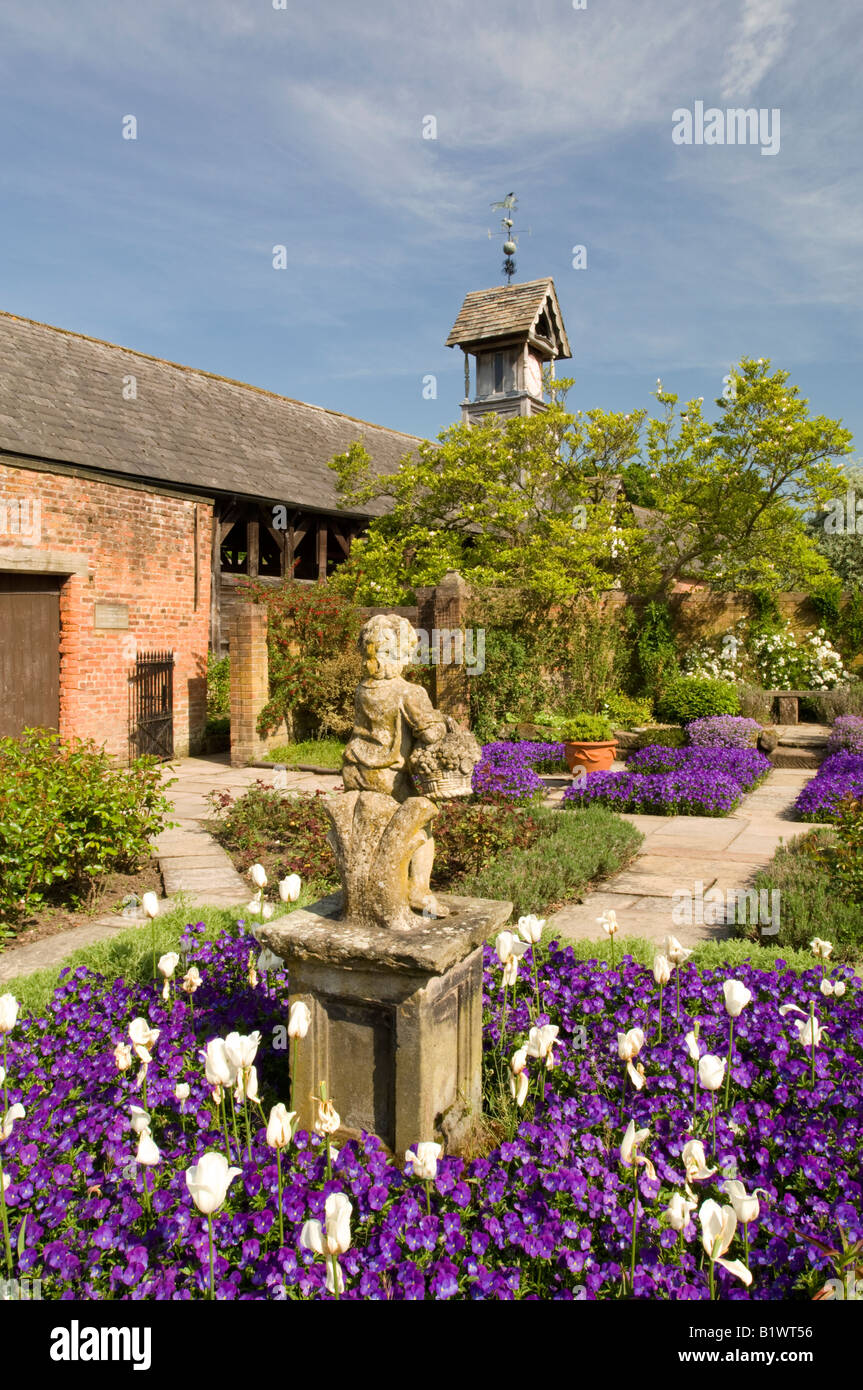 Le viole e tulipani circondano un giardino statua in bandiera giardino, Arley Hall, Arley, Cheshire, Inghilterra, Regno Unito Foto Stock