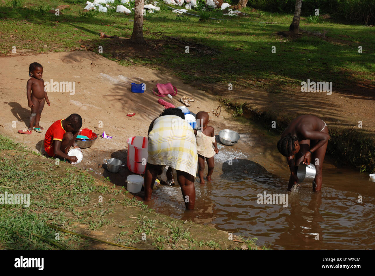 Una donna nera con i suoi bambini stanno facendo il washingup sul lungofiume Maroni in Apatou Guiana francese Foto Stock