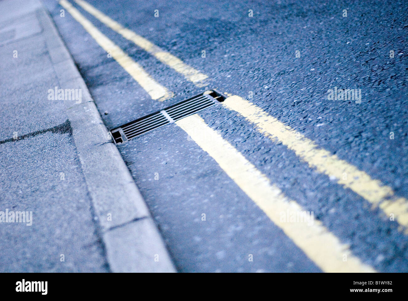 Doppio giallo linee su strada con scarico Foto Stock