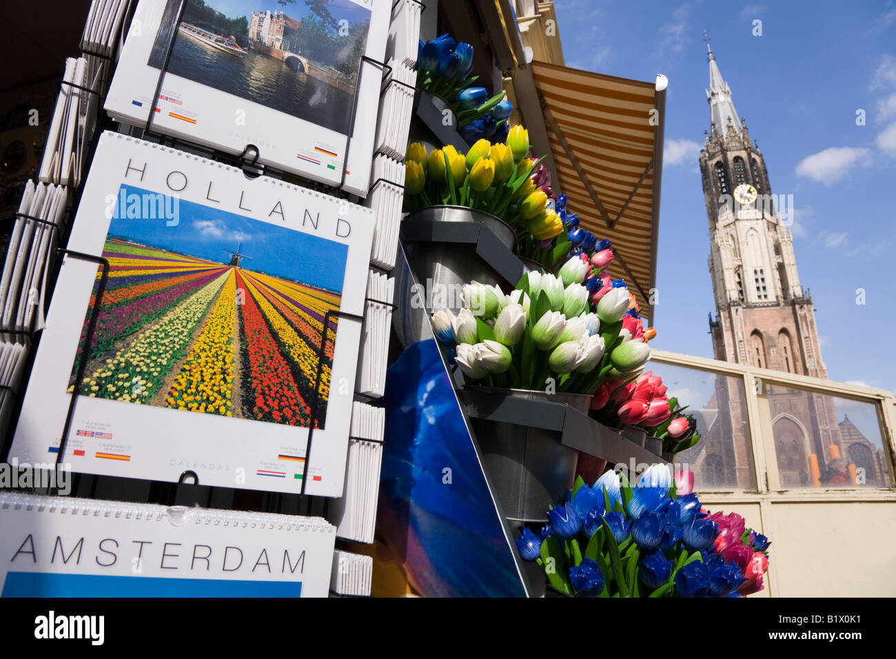 Calendari & tulipani in vendita presso un negozio di Markt Square, Delft. In Olanda. La torre/guglia della Nieuwe Kerk cattedrale è dietro Foto Stock