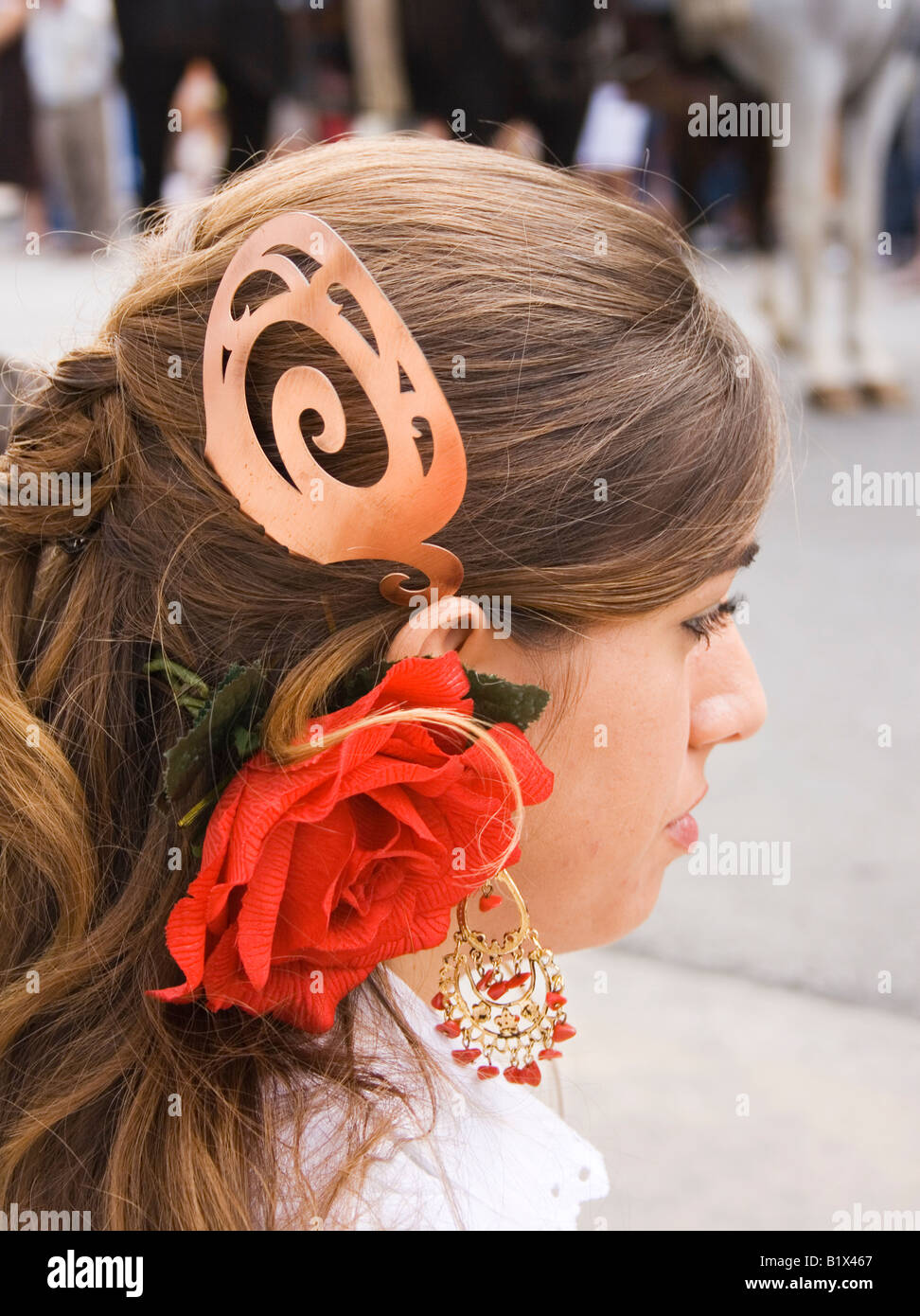 Una giovane ragazza in spagnolo tipico abito rosso con decorazioni di fiori nei capelli Foto Stock