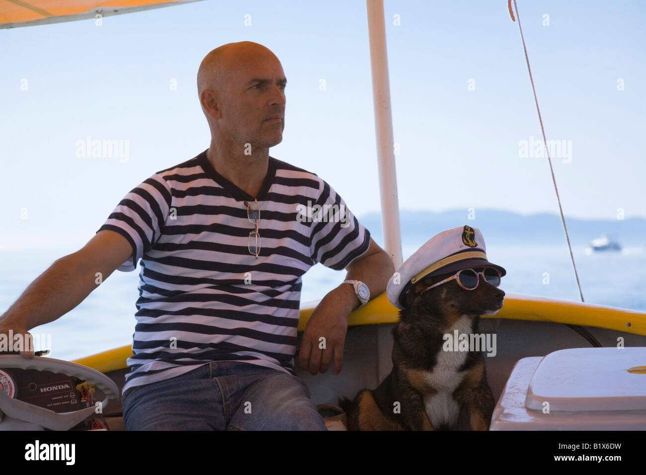 Opatija Istria Croazia Europa un uomo e il suo cane con occhiali da sole e cappello marinaio in turistico barca motoscafo Foto Stock