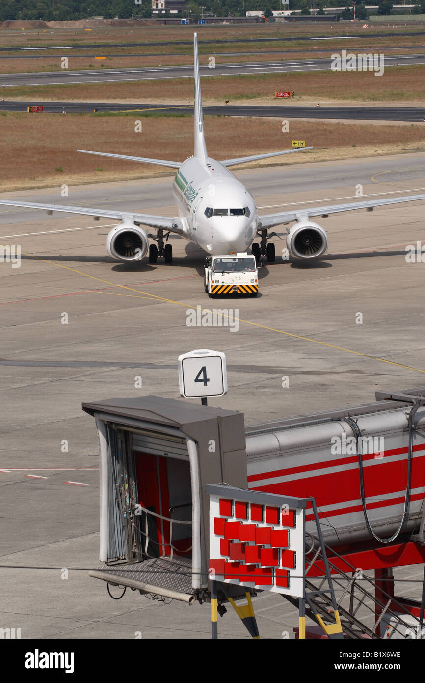 Compagnia aerea Boeing 737 aereo jet aerei essendo spinto da un aeroporto rimorchiatore di traino veicolo trattore con airport terminal gate di partenza Foto Stock