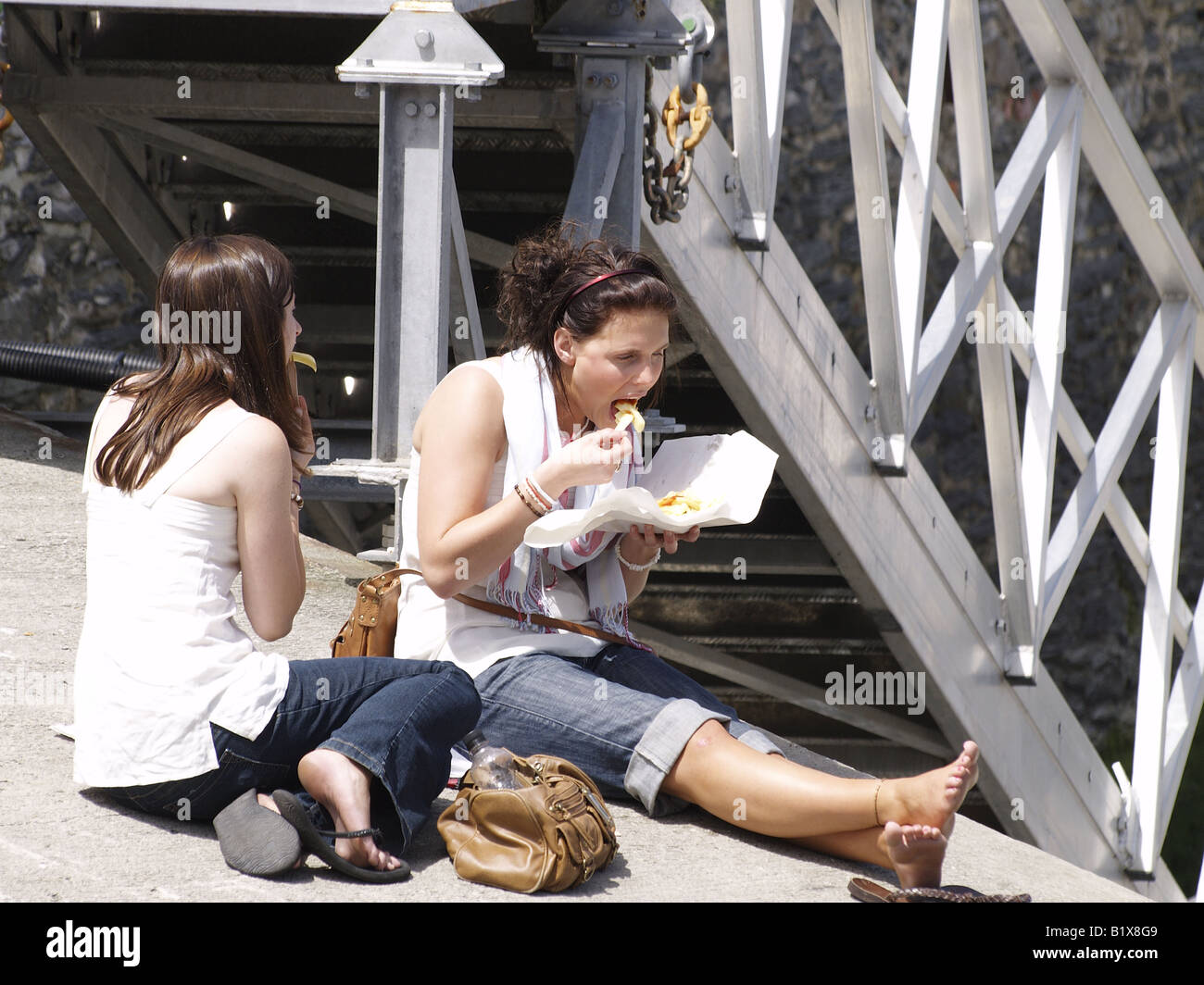 Due giovani donne mangiare patatine Foto Stock