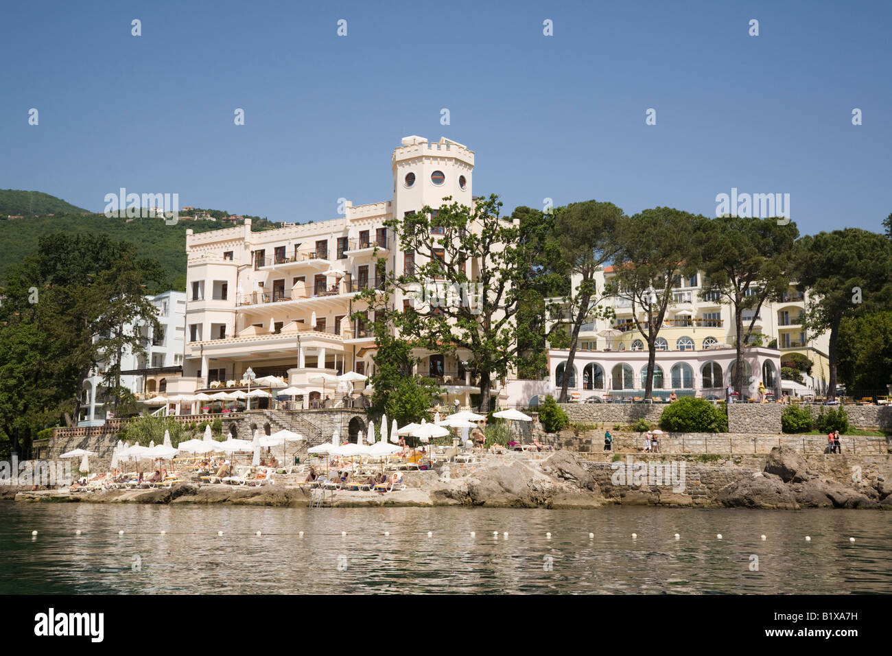 Opatija Istria Croazia Europa vista Offshore di elegante Lungomare Hotel Miramar con la gente a prendere il sole sulla spiaggia di cemento Foto Stock