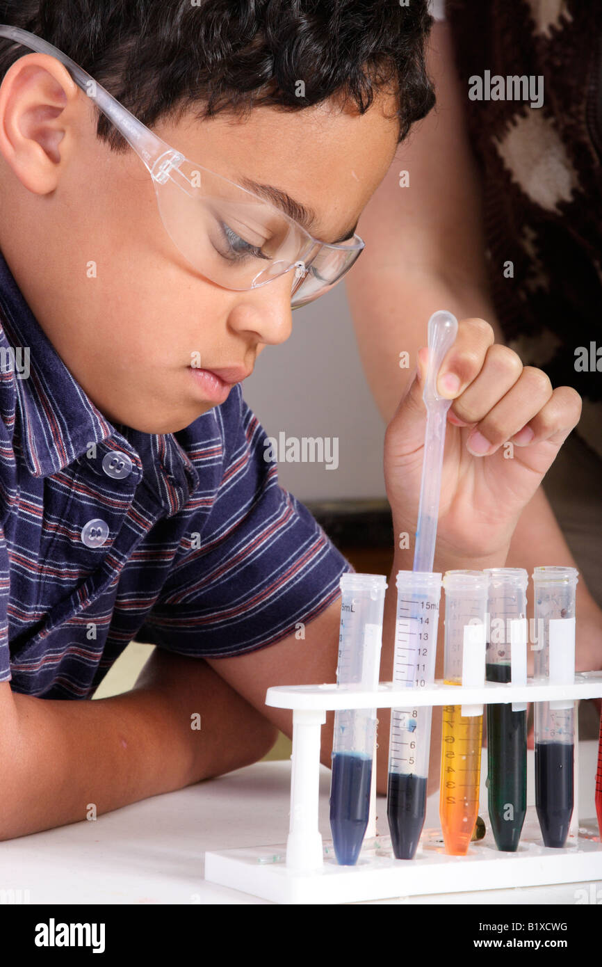 Fotografia di stock di uno studente utilizzando una pipetta per trasferire un fluido tra i tubi di prova Foto Stock