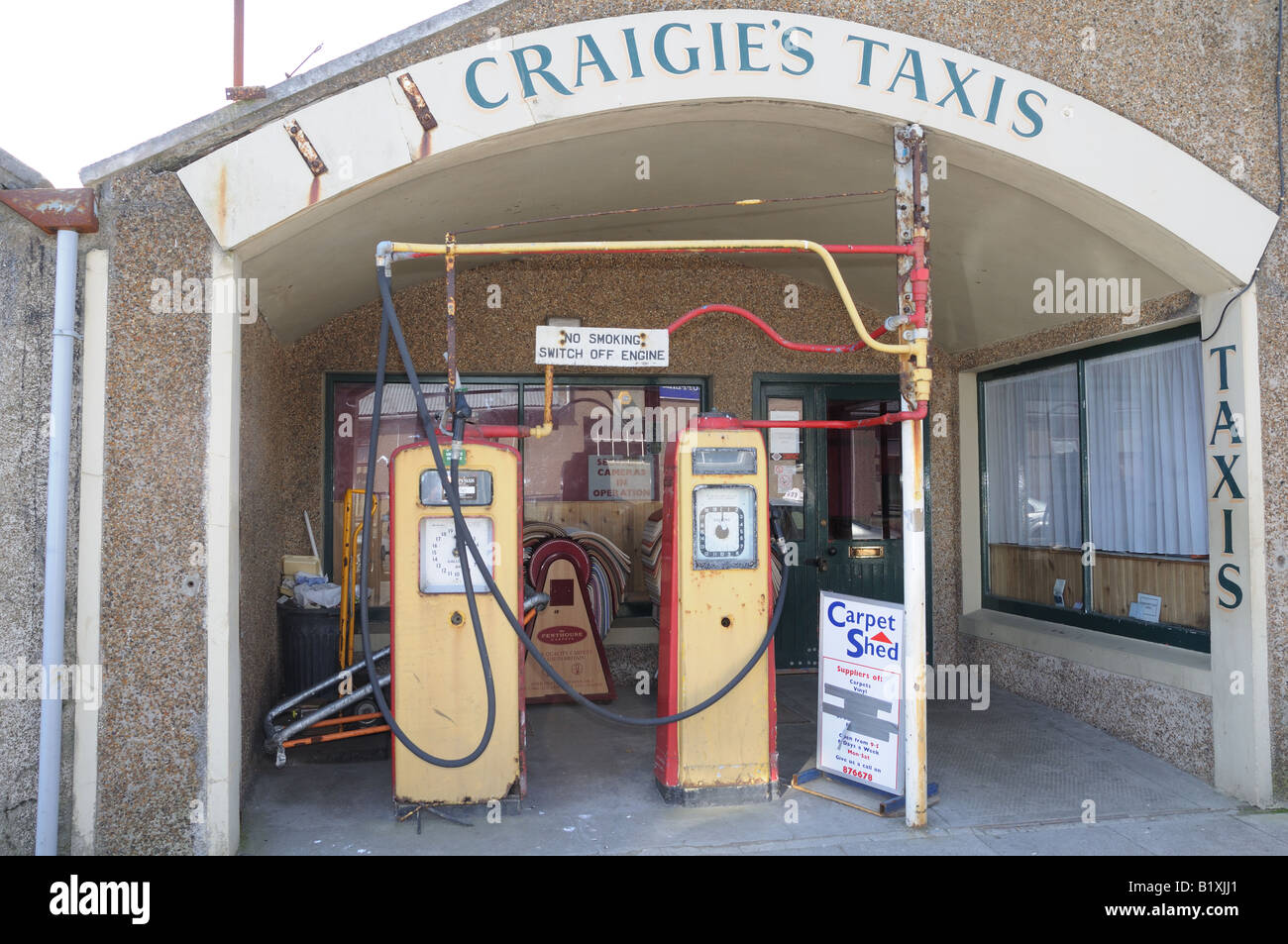 Una vecchia stazione di taxi a Kirkwall, la capitale delle Isole Orkney, ora è un negozio di tappeti ma il gas le pompe restano. Foto Stock