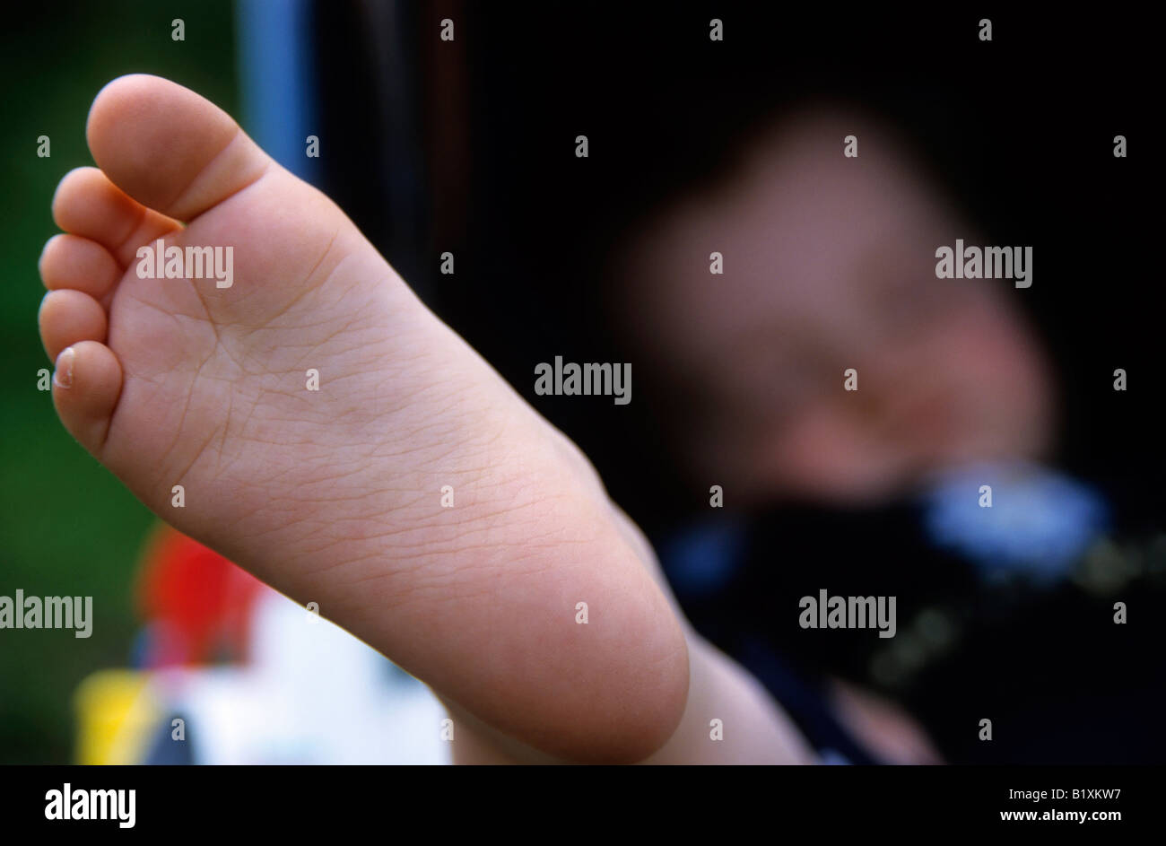 Baby ragazza in piedi vicino mentre lei dorme nel suo passeggino a piedi nudi Foto Stock