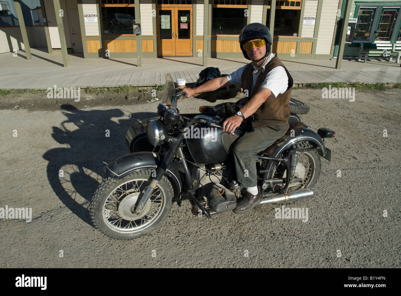 Un uomo e il suo cane su un motociclo di Dawson City, Yukon, Canada. Foto Stock