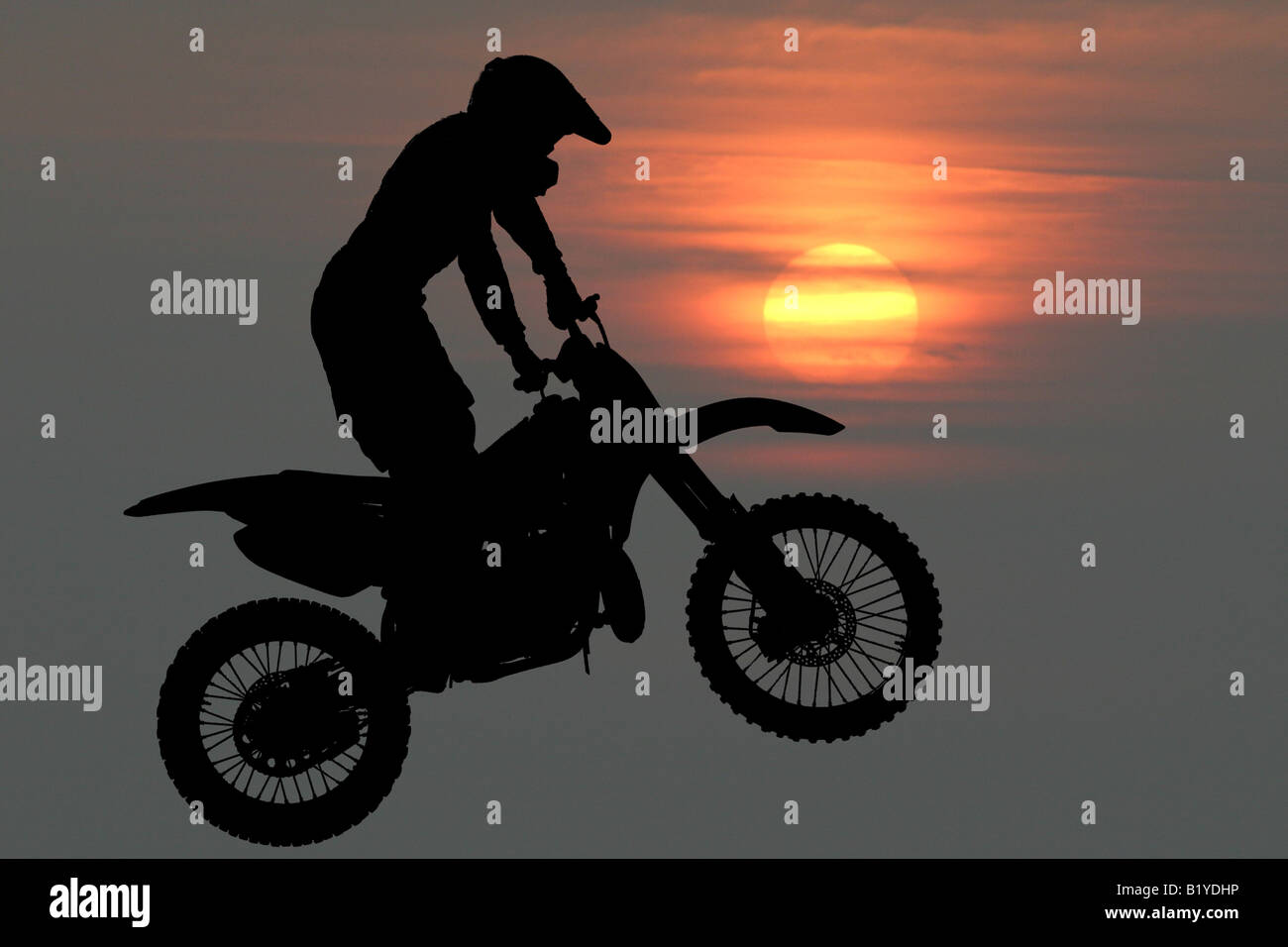 Colpo composito di acrobazie per ciclo motore in occasione di una mostra volare attraverso l'aria incollato sul Cielo di tramonto sullo sfondo. Foto Stock