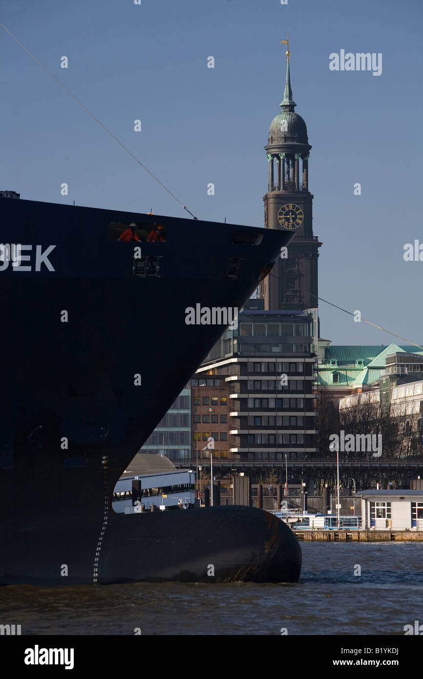 La prua di un contenitore freighter passando la guglia della principale di Amburgo chiesa di St Michaelis chiamato Michel Foto Stock