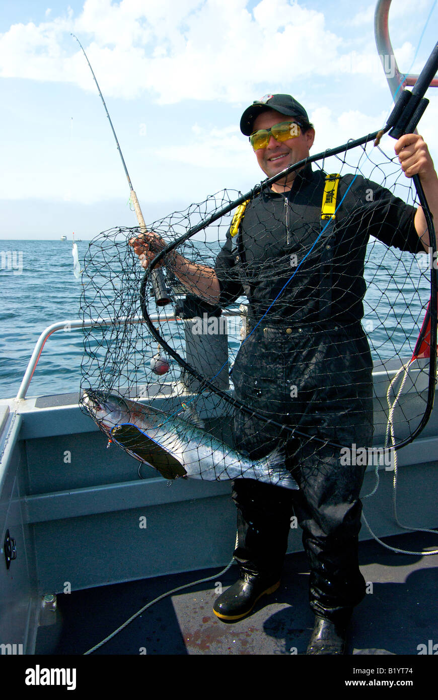 Uomo con sport troll catturati argento coho salmone sbarcato in net catturati pesca troll Foto Stock