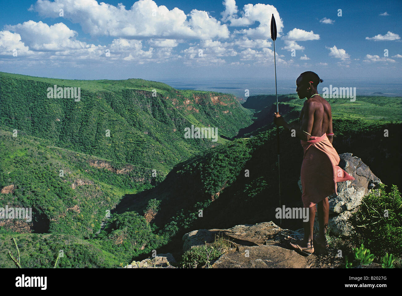Samburu guerriero o moran in abito tradizionale armati di lancia guardando giù il El Kajarta Gorge dal Monte Kulal nel nord del Kenya Foto Stock
