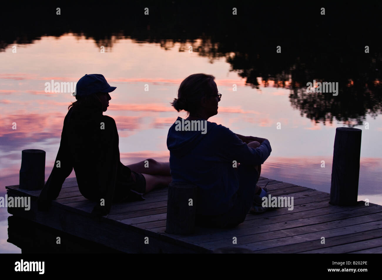 Madre e figlia ubicazione sul Dock stagliano contro la riflessione del tramonto Mount Saint Francis Indiana Foto Stock