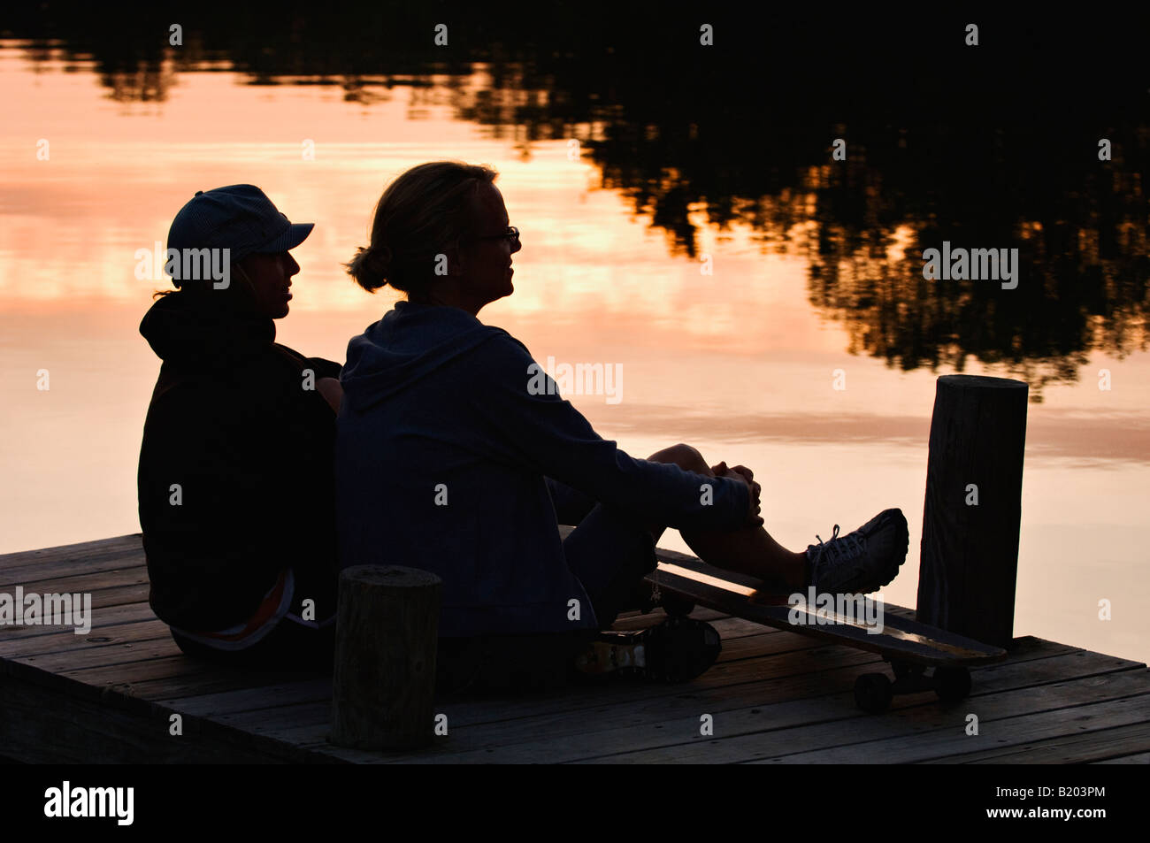 Madre e figlia ubicazione sul Dock stagliano contro la riflessione del tramonto Mount Saint Francis Indiana Foto Stock