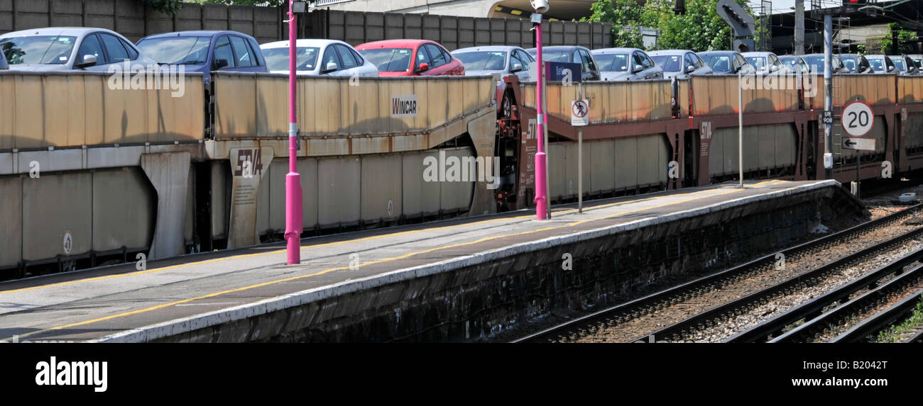 Primo piano di carri a due piani su un treno merci che trasporta un carico di auto nuove che viaggiano attraverso la stazione ferroviaria di East London, Inghilterra, Regno Unito Foto Stock