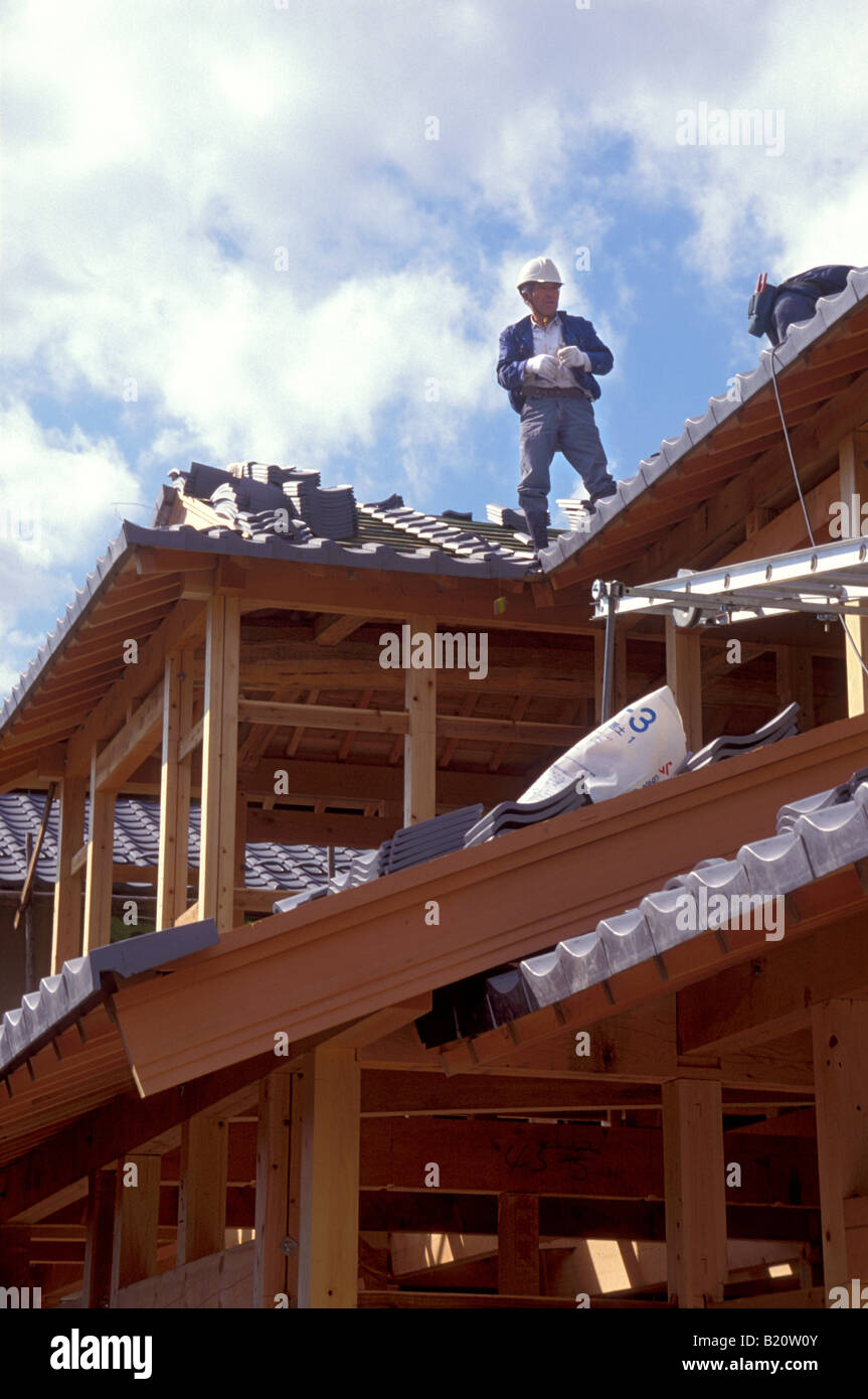 Operaio della costruzione di un edificio in stile tradizionale giapponese residence in piedi sul nuovo tetto di tegole Foto Stock