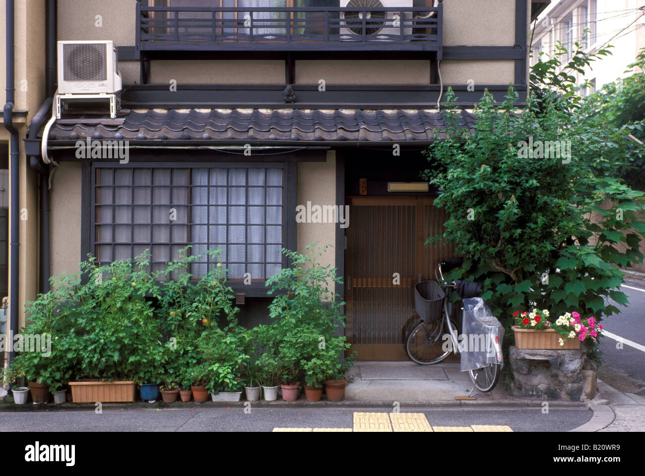Un tipico stile machiya a due piani residenza nella città di Kyoto con vasi di piante di fronte al bordo della strada. Foto Stock