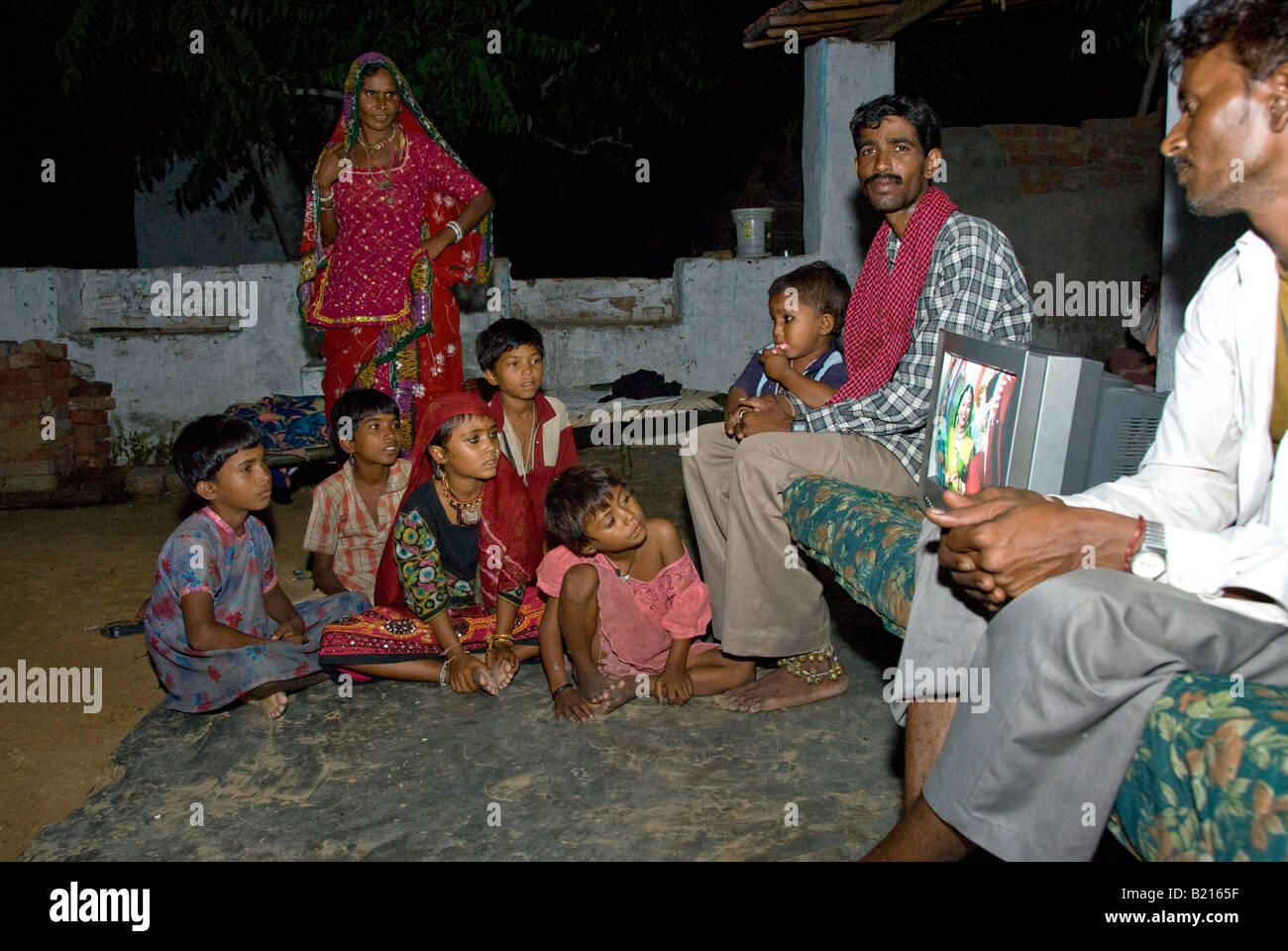 I bambini di Rajasthani guardando un tradizionale programma televisivo su un televisore nel cortile di casa propria, Rajasthan (India). Foto Stock