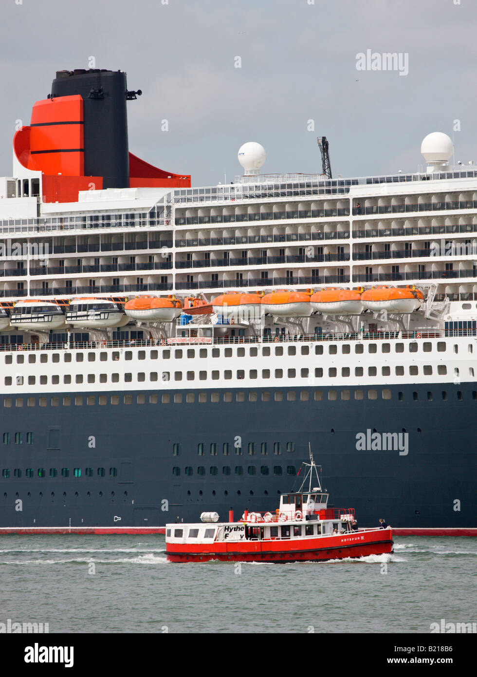 L'Hythe traghetto è sopraffatte dagli enormi Cunard transatlantico Queen Mary 2 mentre è inserito in Southampton Hampshire Inghilterra Foto Stock