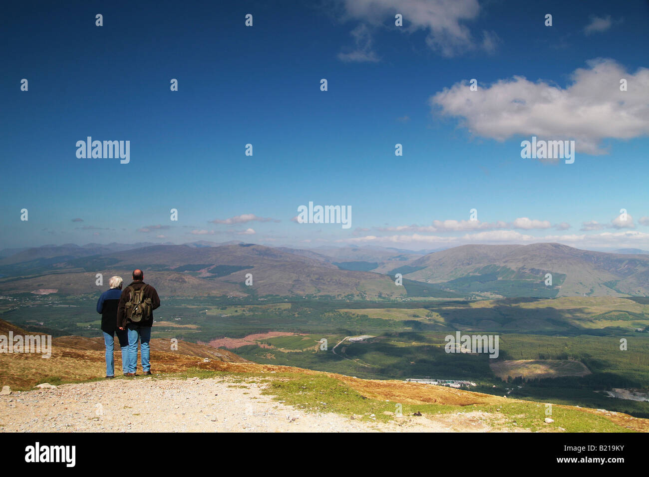 Due persone che stavano in piedi in cima a una montagna ammirando la vista Foto Stock