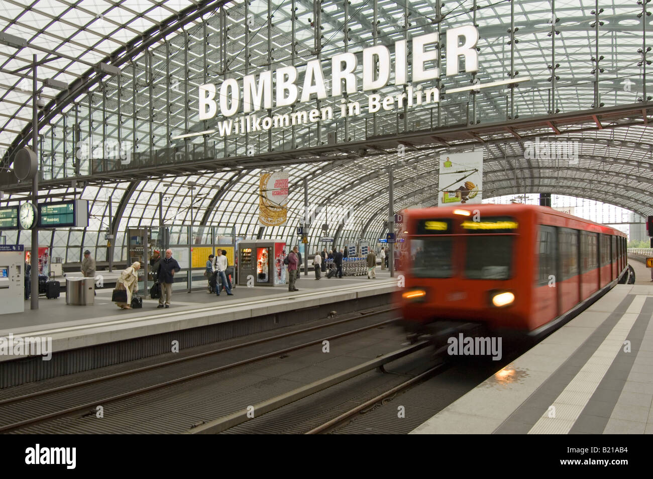 Un treno locale tirando in Berlino stazione centrale di livello superiore con i passeggeri sulla piattaforma e Benvenuti a Berlino segno. Foto Stock