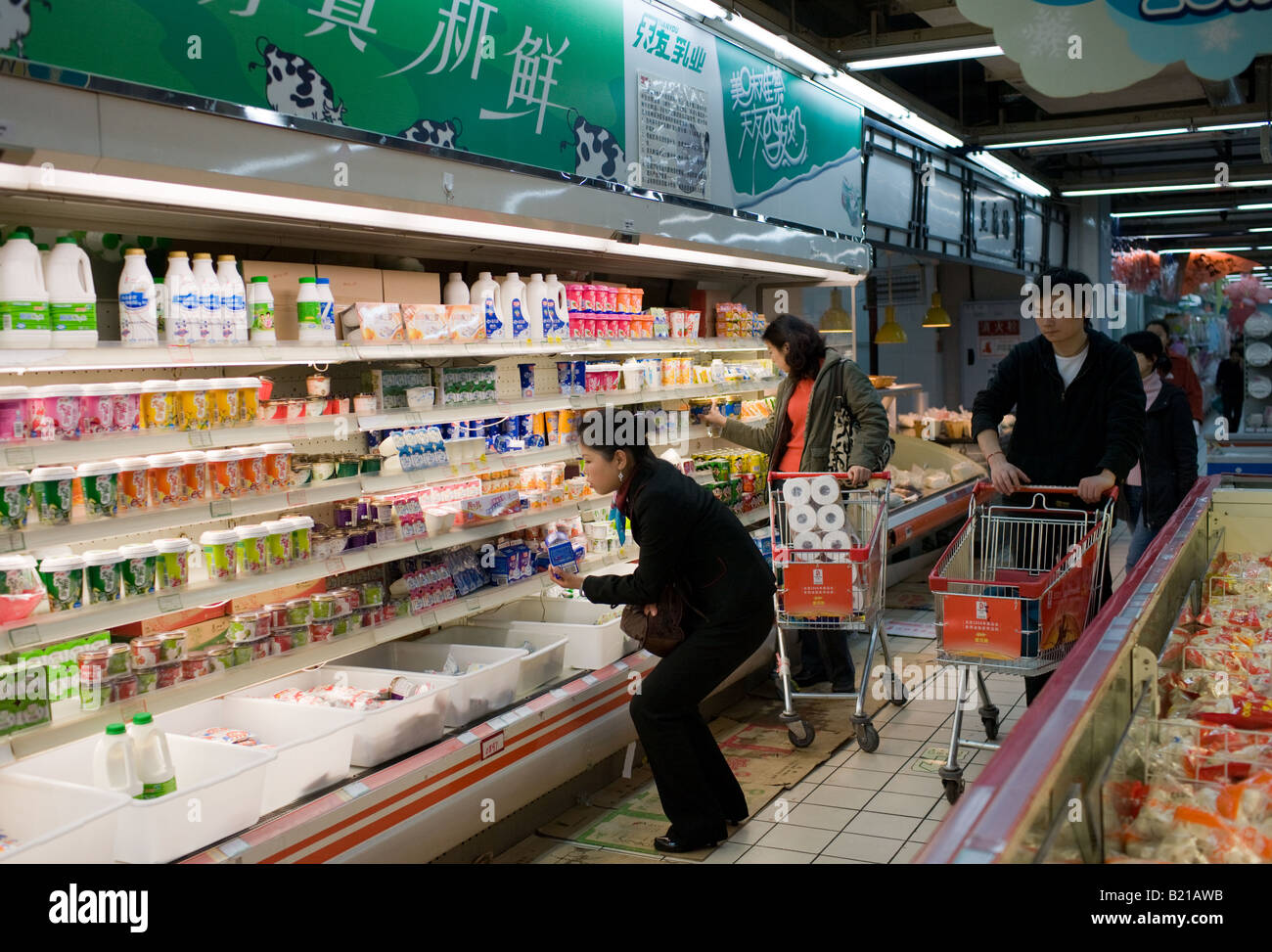 Le persone con carrelli della spesa acquisto di latte e altri prodotti cinesi in un supermercato a Chongqing nella provincia del Sichuan in Cina Foto Stock