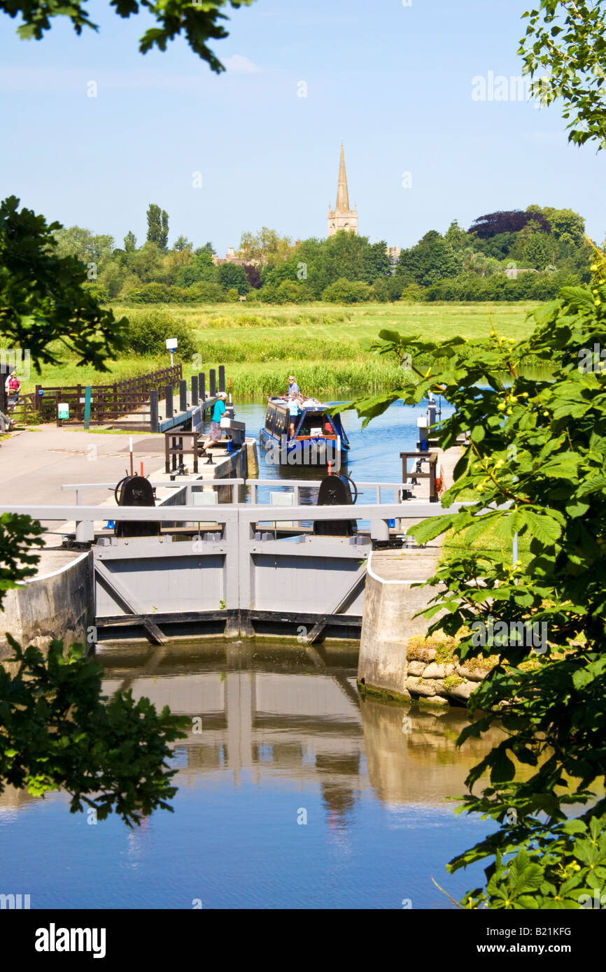 Narrowboat avvicinando St.John's bloccare sul Tamigi, San Lorenzo chiesa guglia in background, a Lechlade, Gloucestershire, Regno Unito Foto Stock
