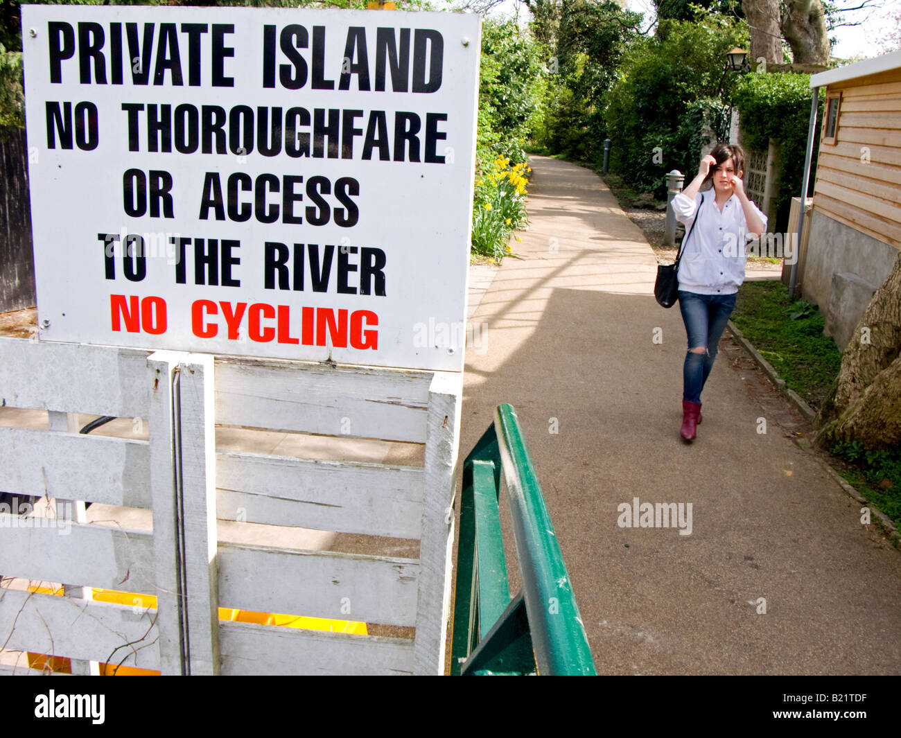 Giovane donna cammina verso un isola privata segno all'ingresso pedonale punto di anguilla isola a torta, Twickenham, Inghilterra Foto Stock
