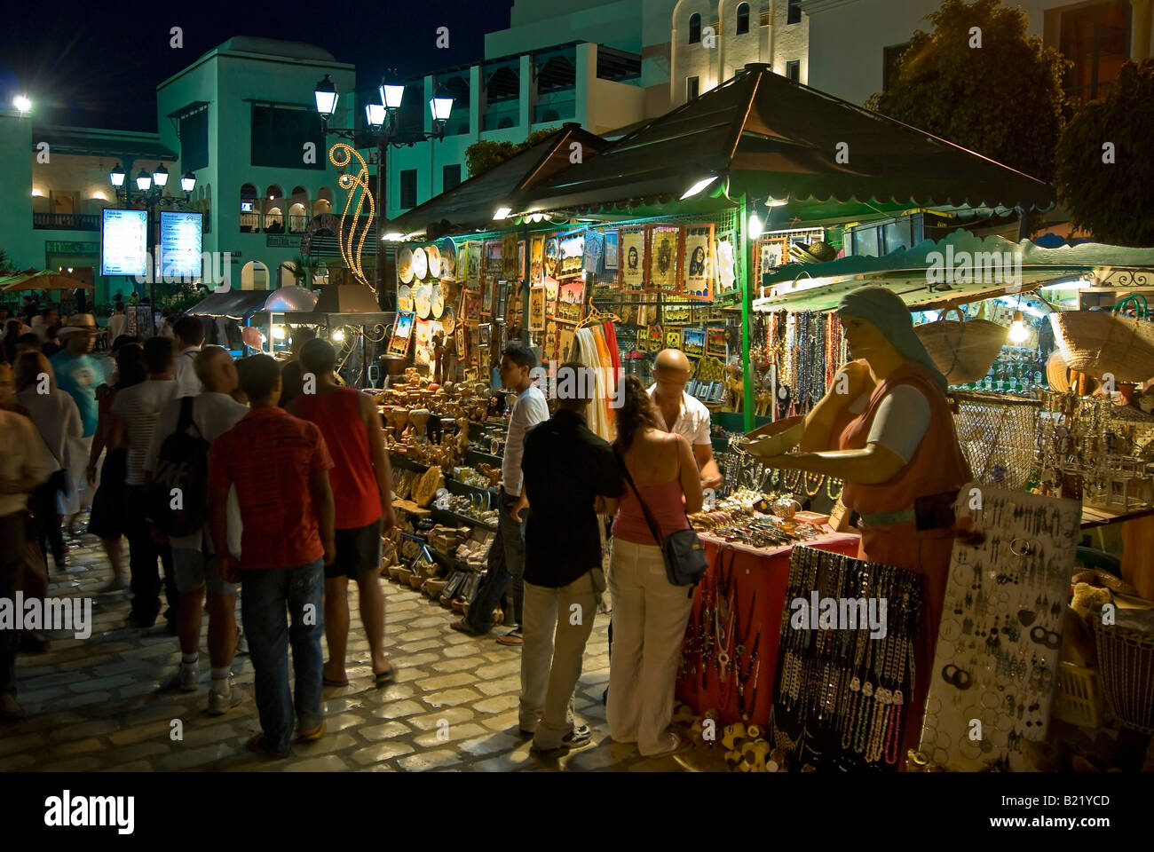 Orizzontale di ampio angolo di turisti a piedi attorno a artigianato tradizionale con bancarelle e negozi all'interno della Medina di notte. Foto Stock