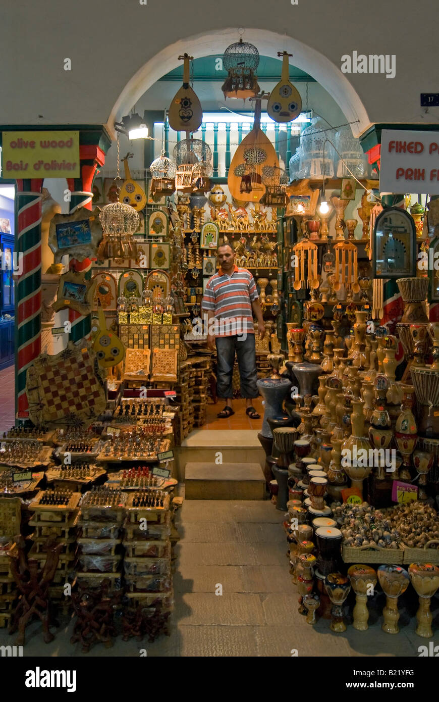Verticale tempo di notte vista al di fuori di un tradizionale tunisino negozio olivewood piena di vari souvenir per i turisti Foto Stock